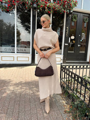 Woman wearing a beige knit two piece sweater set with midi skirt and belt.