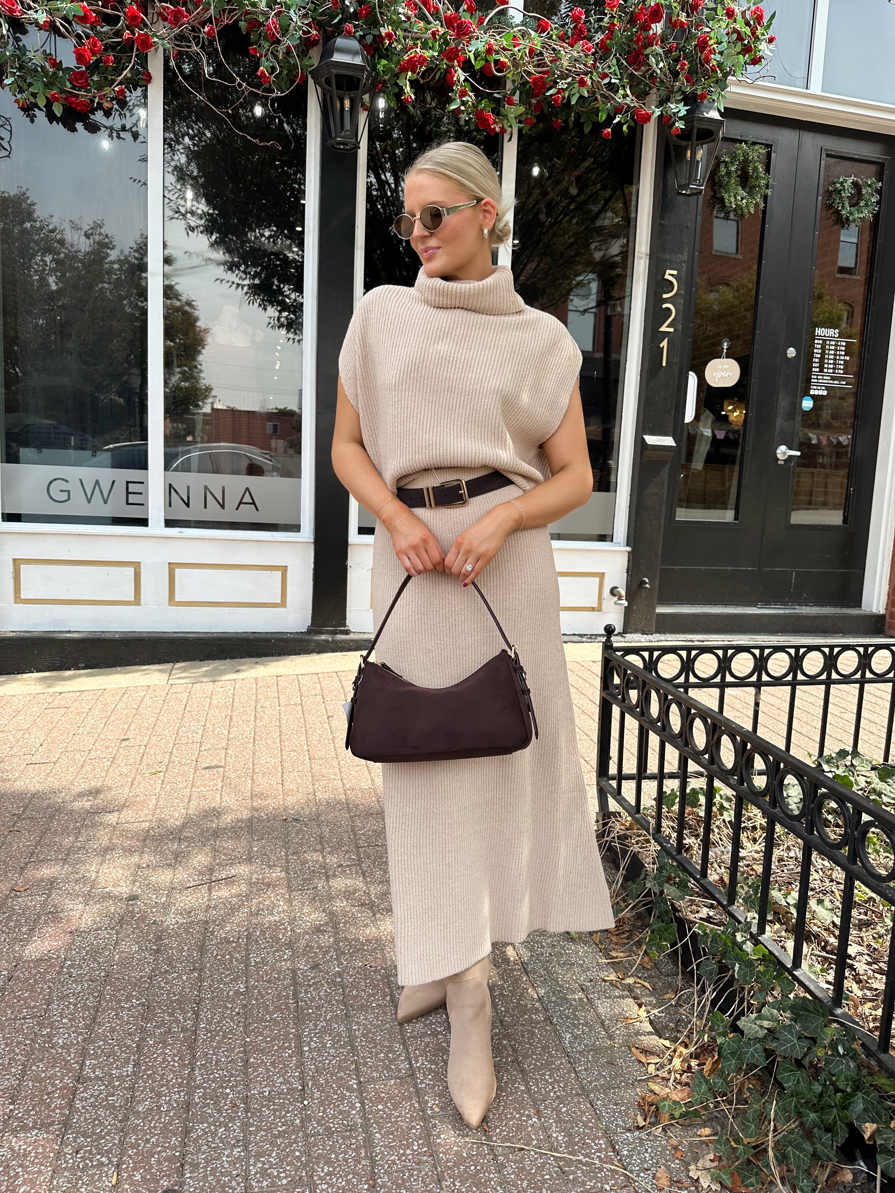 Woman wearing a beige knit two piece sweater set with midi skirt and belt.
