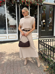 Woman wearing a beige knit two piece sweater set with midi skirt and belt.
