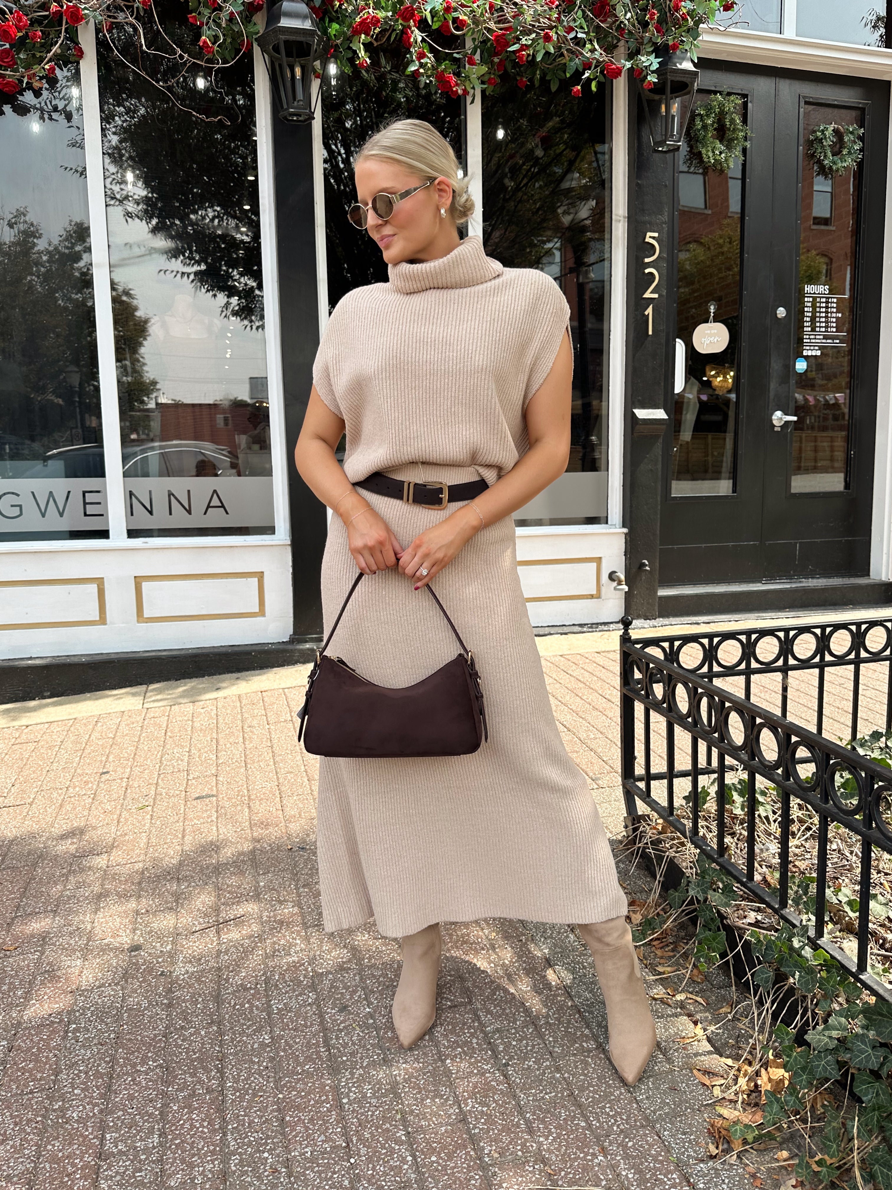 Woman wearing a beige knit two piece sweater set with midi skirt and belt.