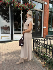 Woman wearing a beige knit two piece sweater set with midi skirt and belt.