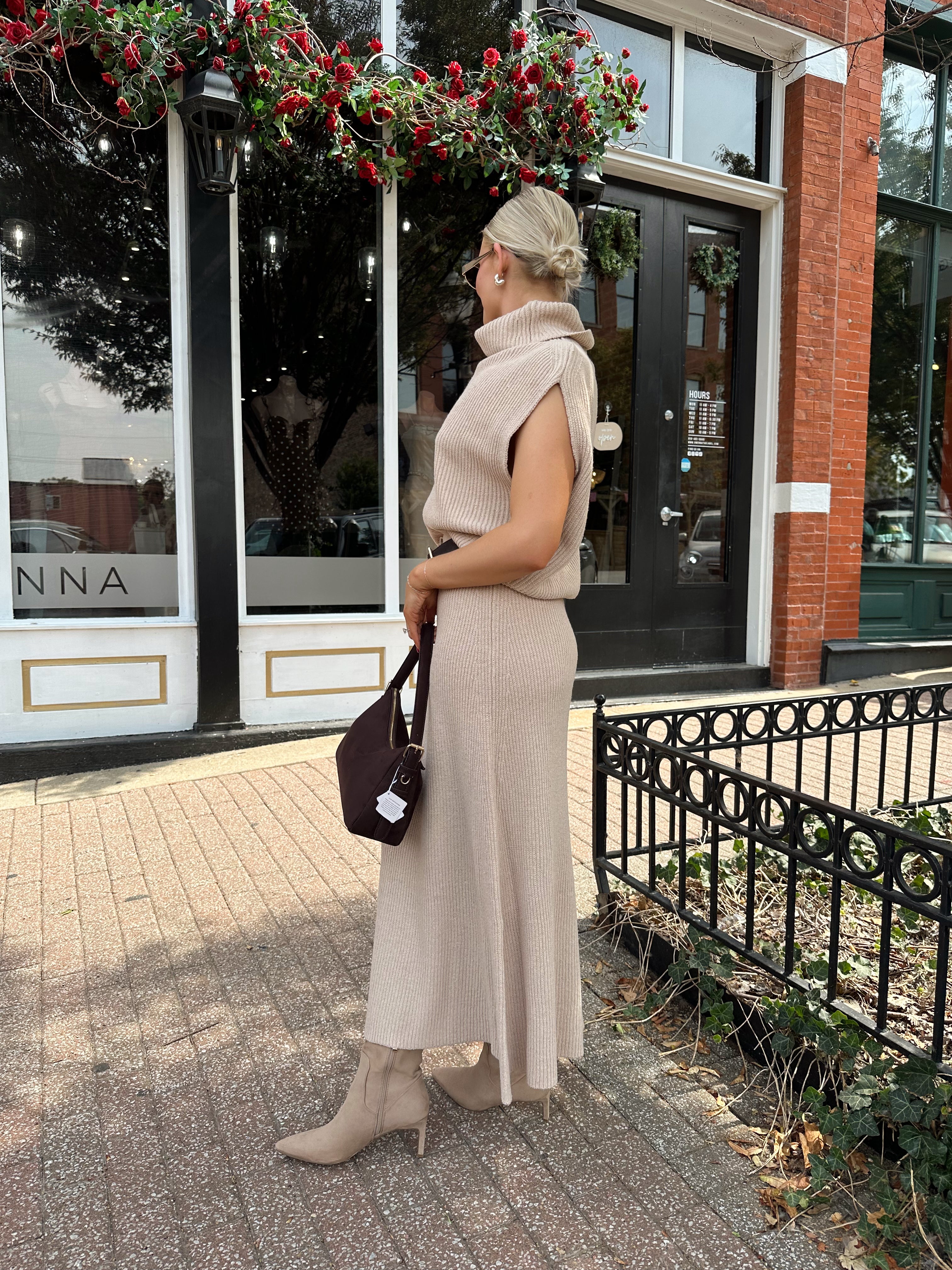Woman wearing a beige knit two piece sweater set with midi skirt and belt.
