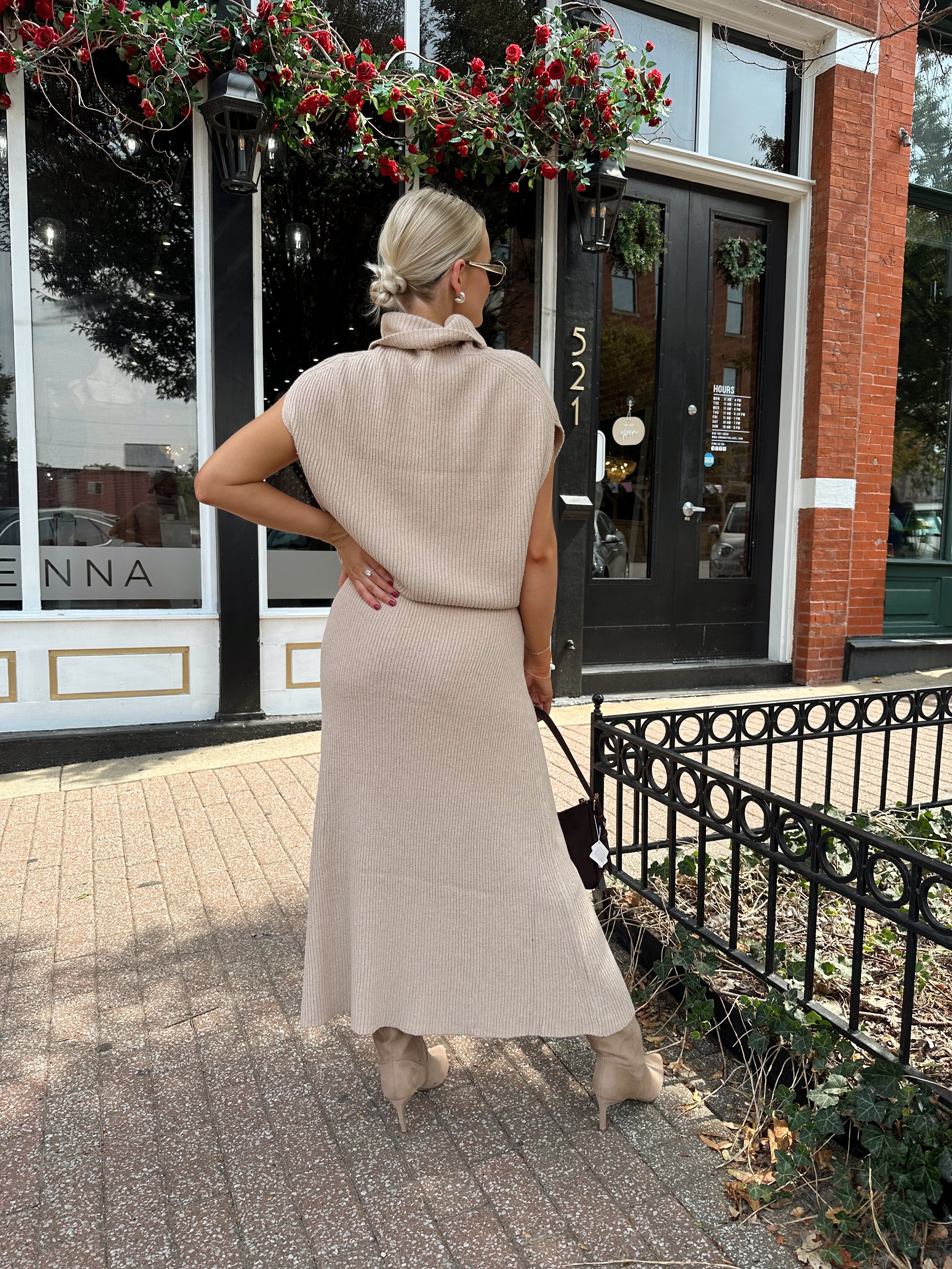 Woman wearing a beige knit two piece sweater set with midi skirt and belt.