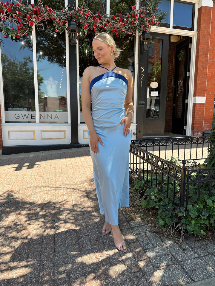 Woman wearing a blue two toned satin maxi dress with a halter neckline, open back, and adjustable straps. 
