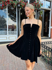 Woman in a black dress standing on a street with a building in the background