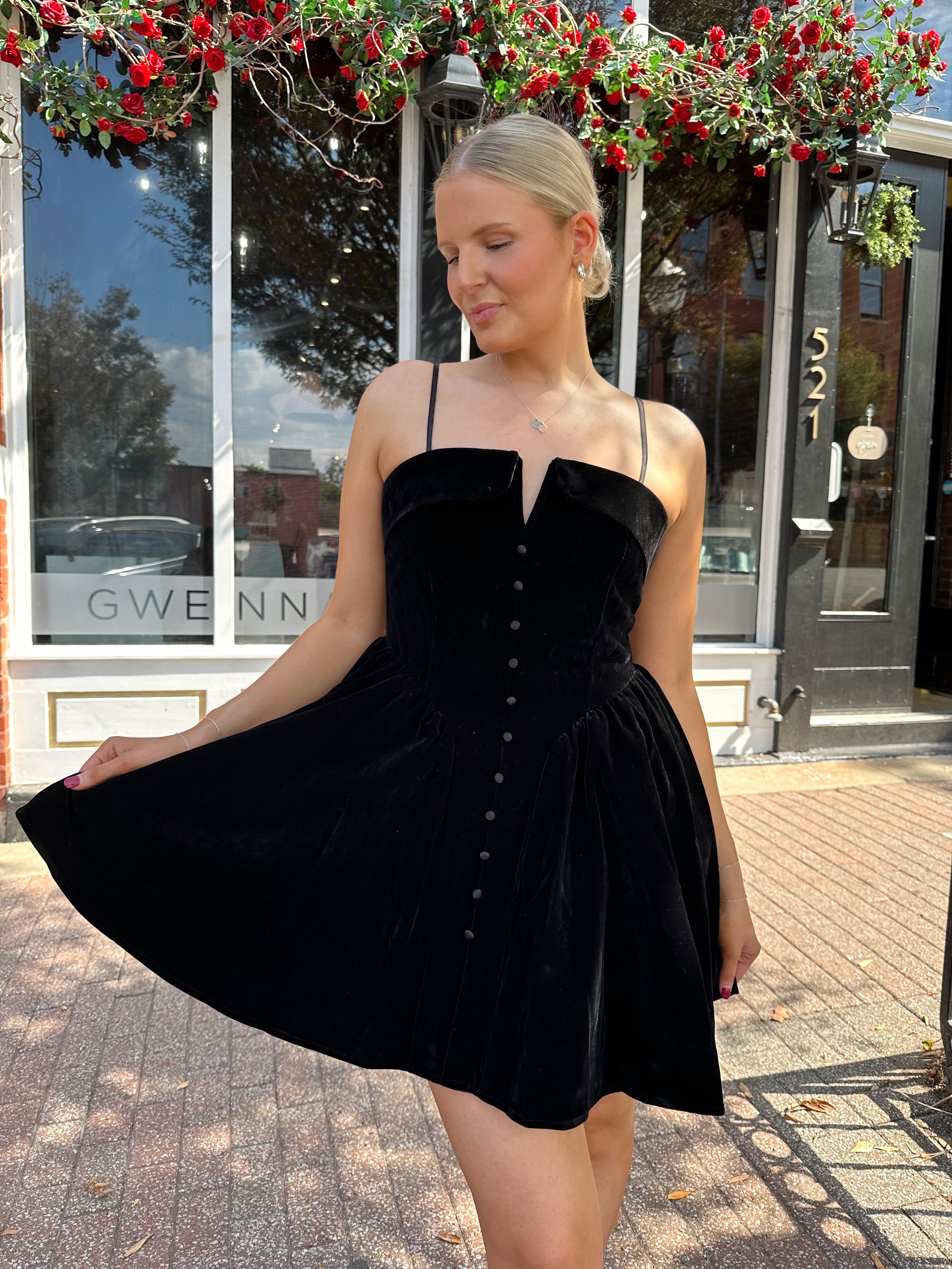 Woman in a black dress standing on a street with a building in the background