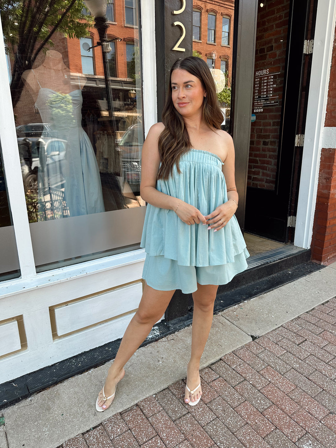Woman wearing mint blue flowy two piece set with strapless top, and high waisted short. 
