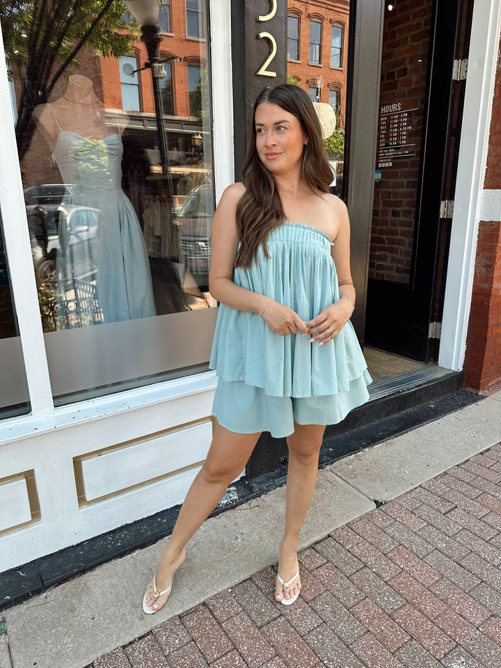 Woman wearing mint blue flowy two piece set with strapless top, and high waisted short. 