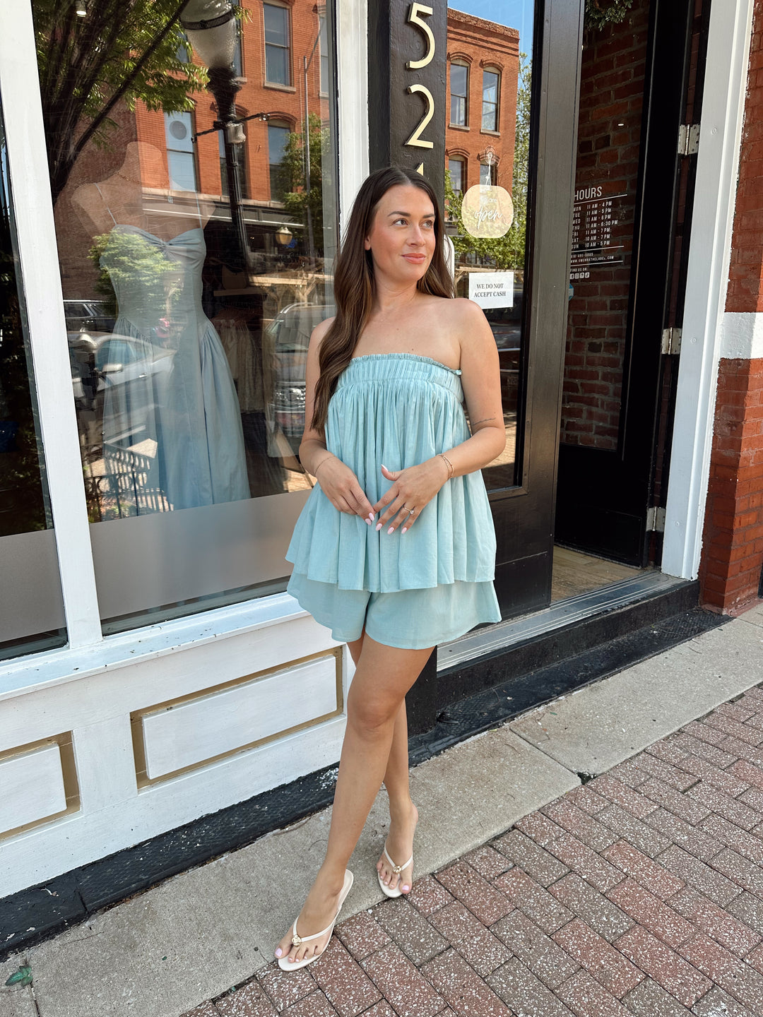 Woman wearing mint blue flowy two piece set with strapless top, and high waisted short. 