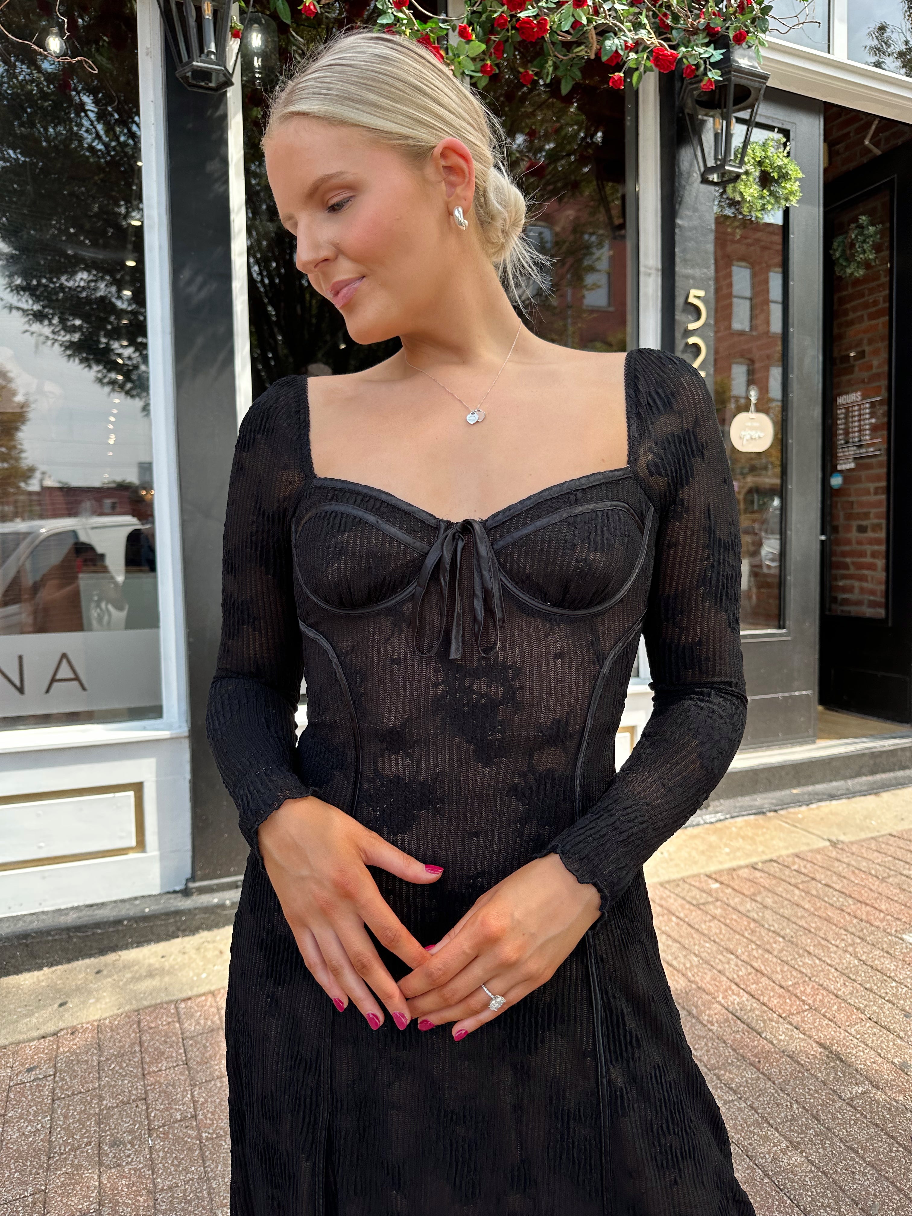 Woman wearing long sleeve black lace midi dress with tan underlay. 