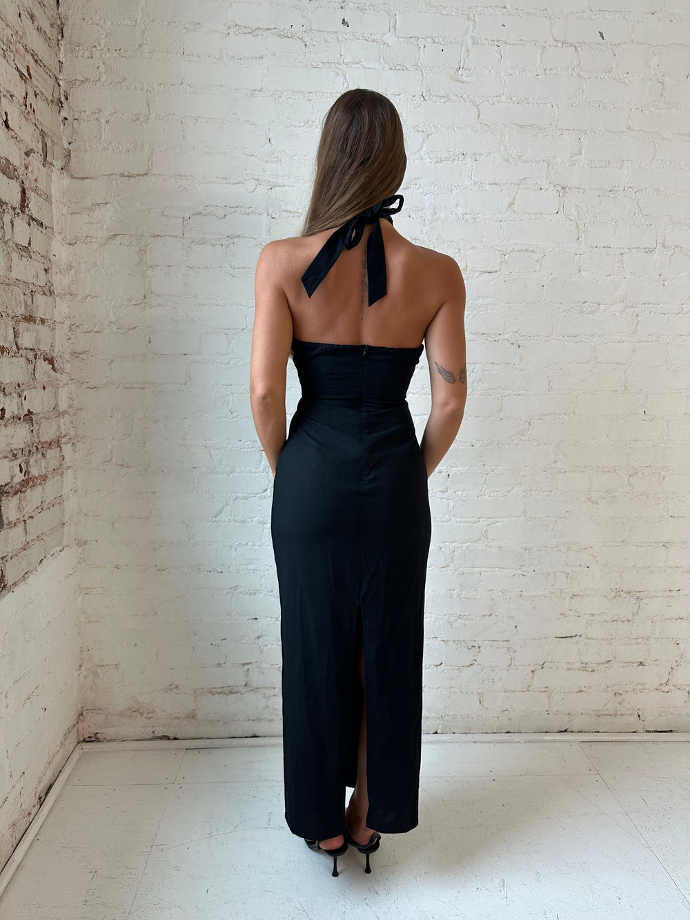 Woman wearing black key hole midi dress with self tie halter and knot detailing. 