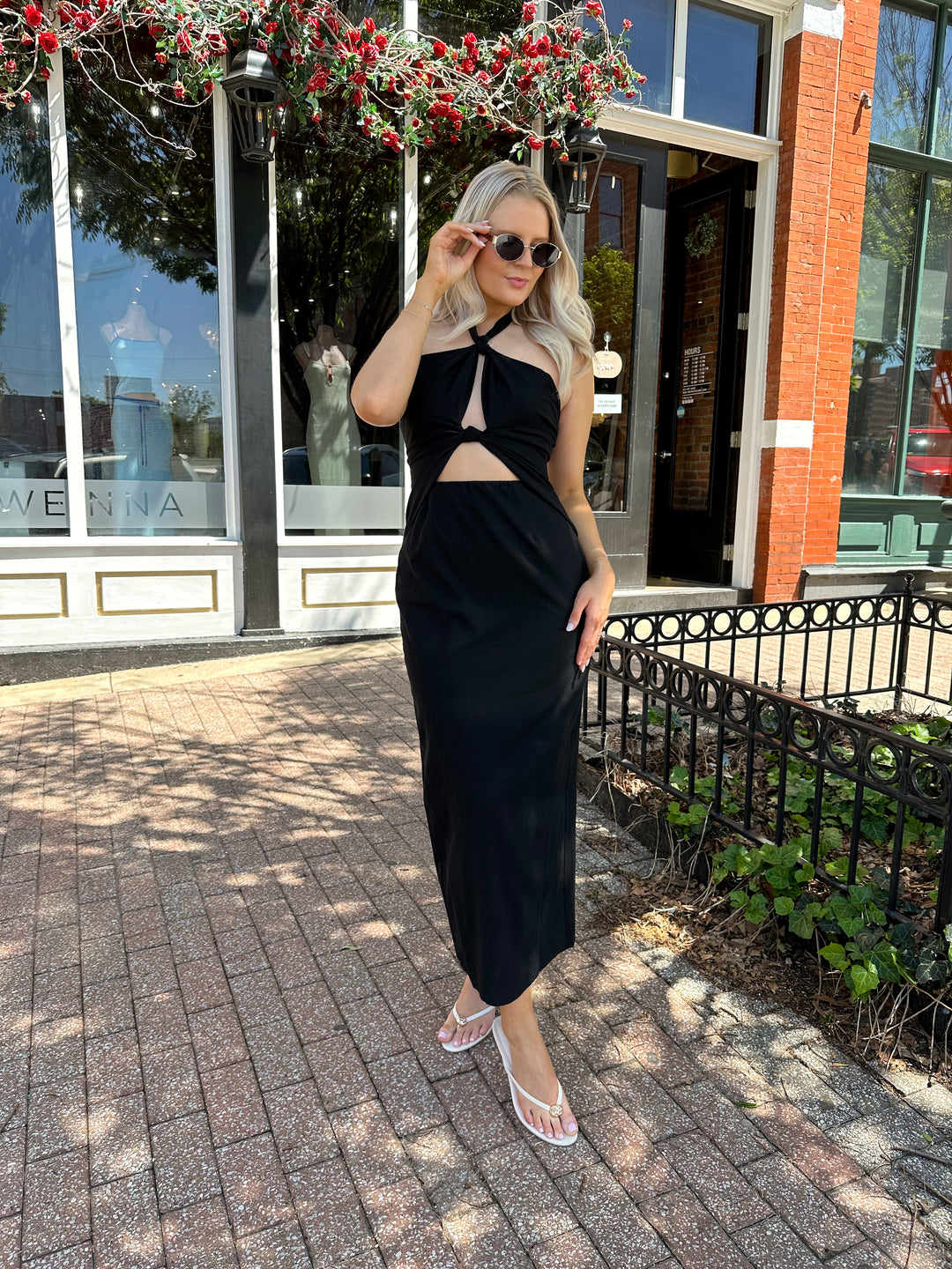 Woman wearing black key hole midi dress with self tie halter and knot detailing. 