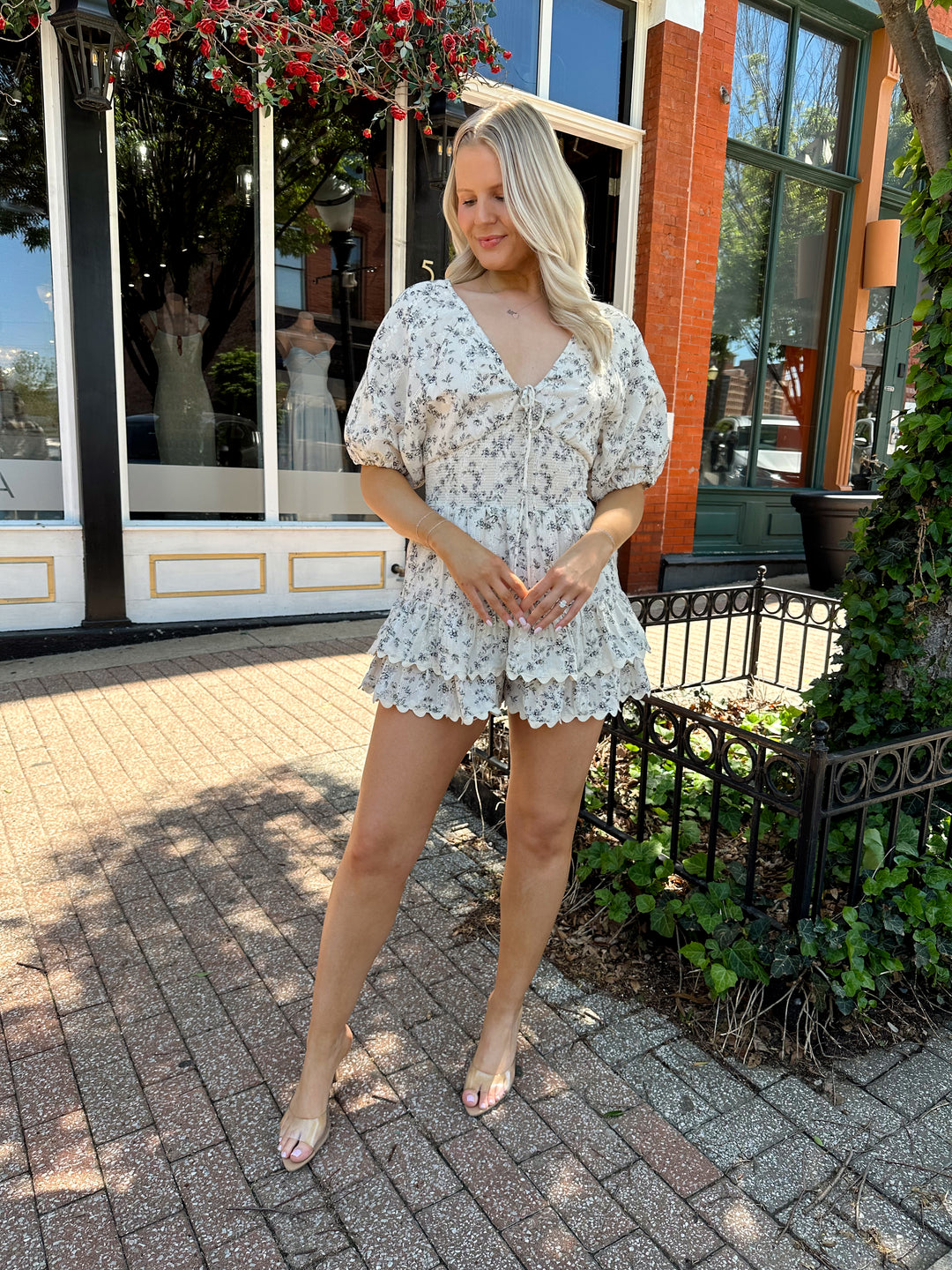 Woman wearing white romper with black floral pattern, tiered short. 
