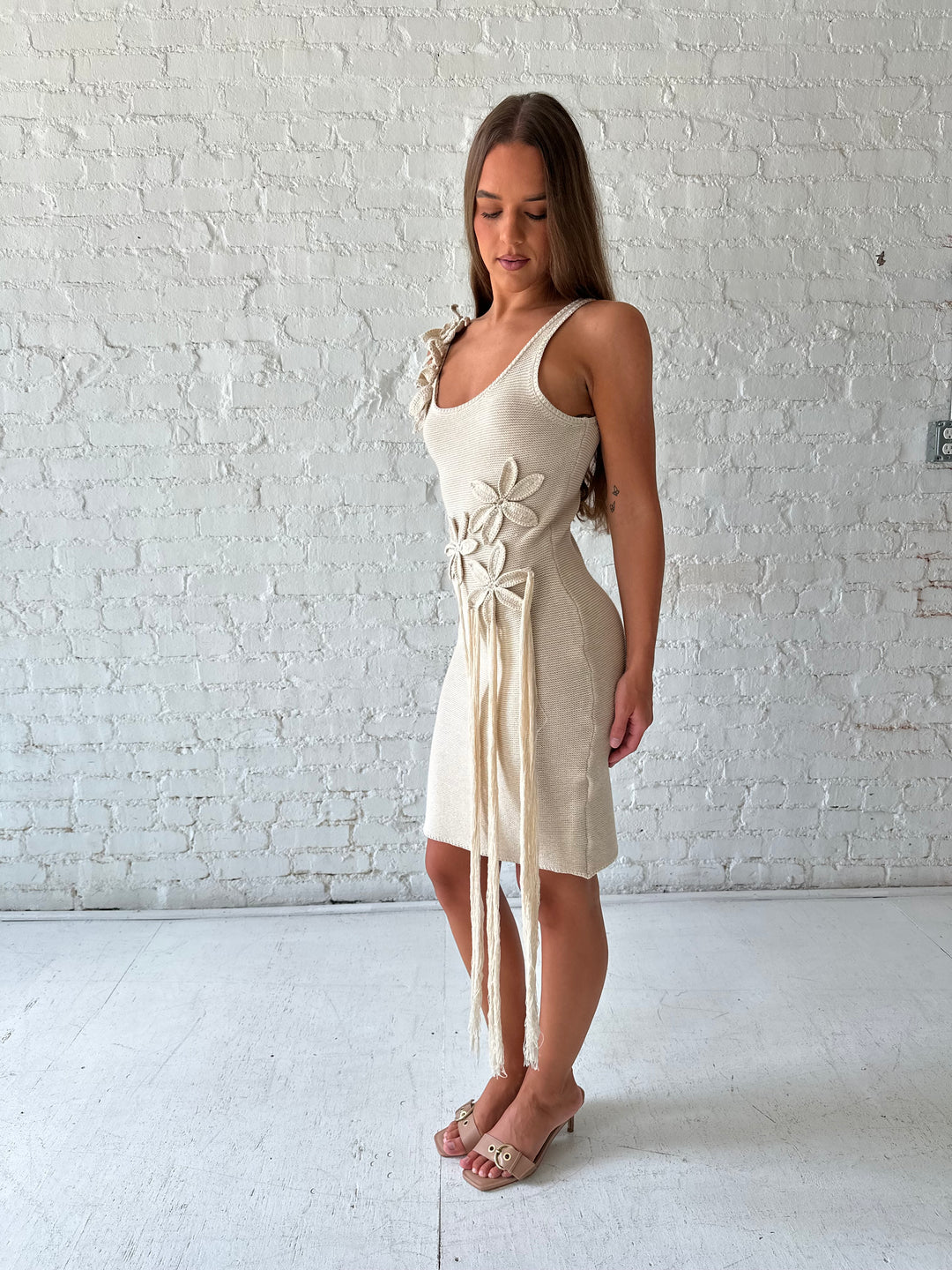 Woman wearing beige knit mini dress with 3D floral appliqué.