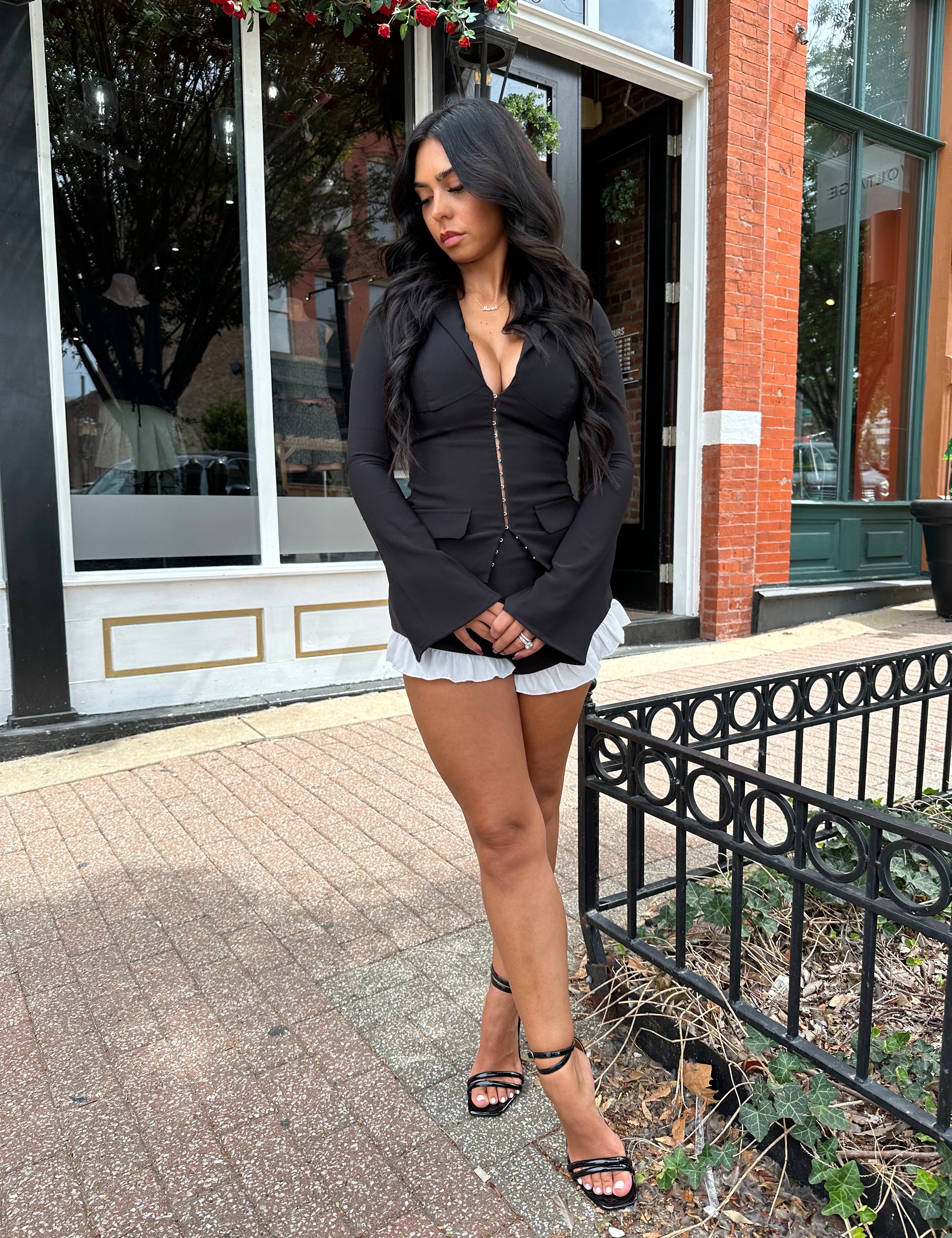 Woman wearing black long sleeve top with clasp closure. 
