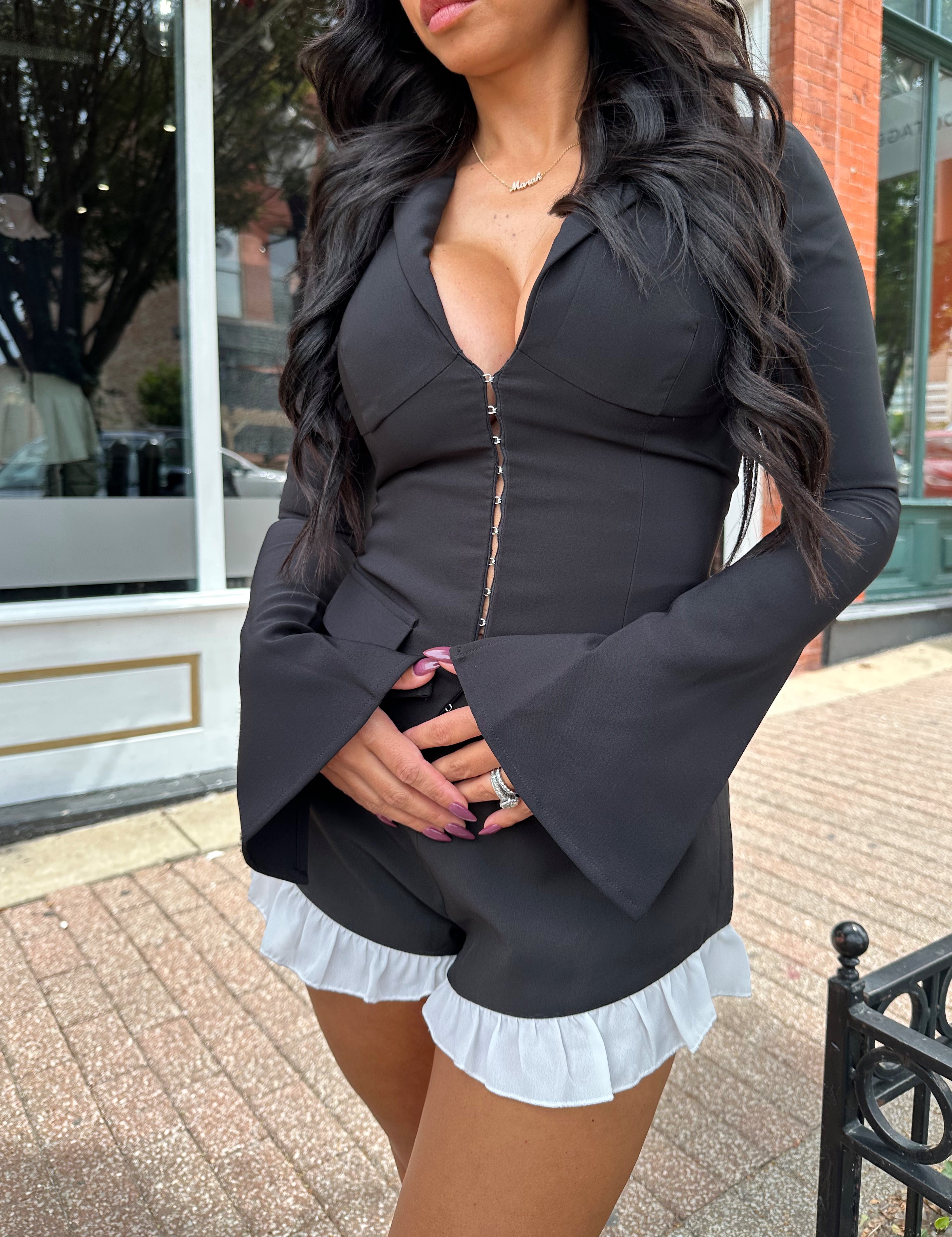 Woman wearing black long sleeve top with clasp closure. 