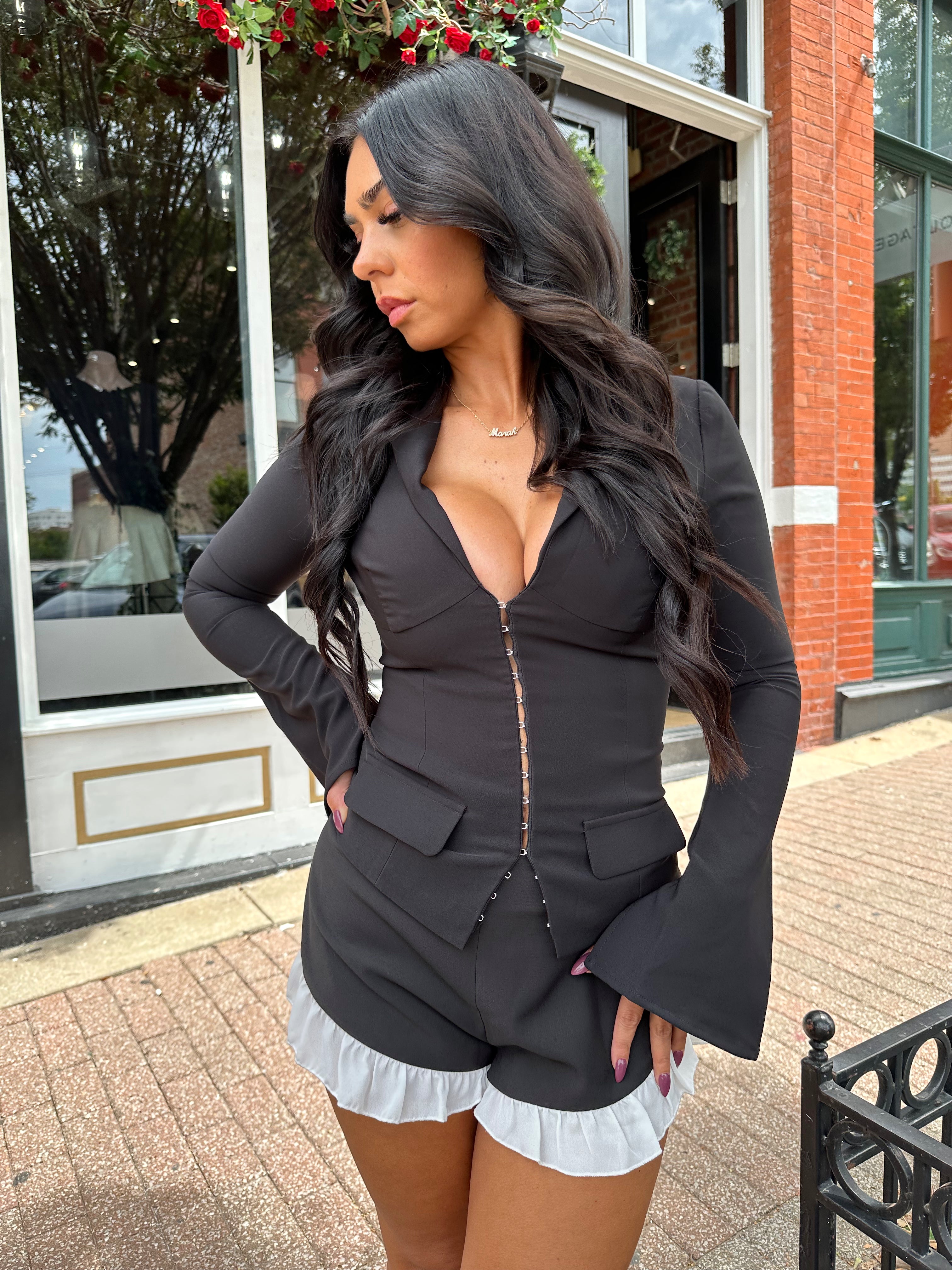 Woman wearing black long sleeve top with clasp closure. 