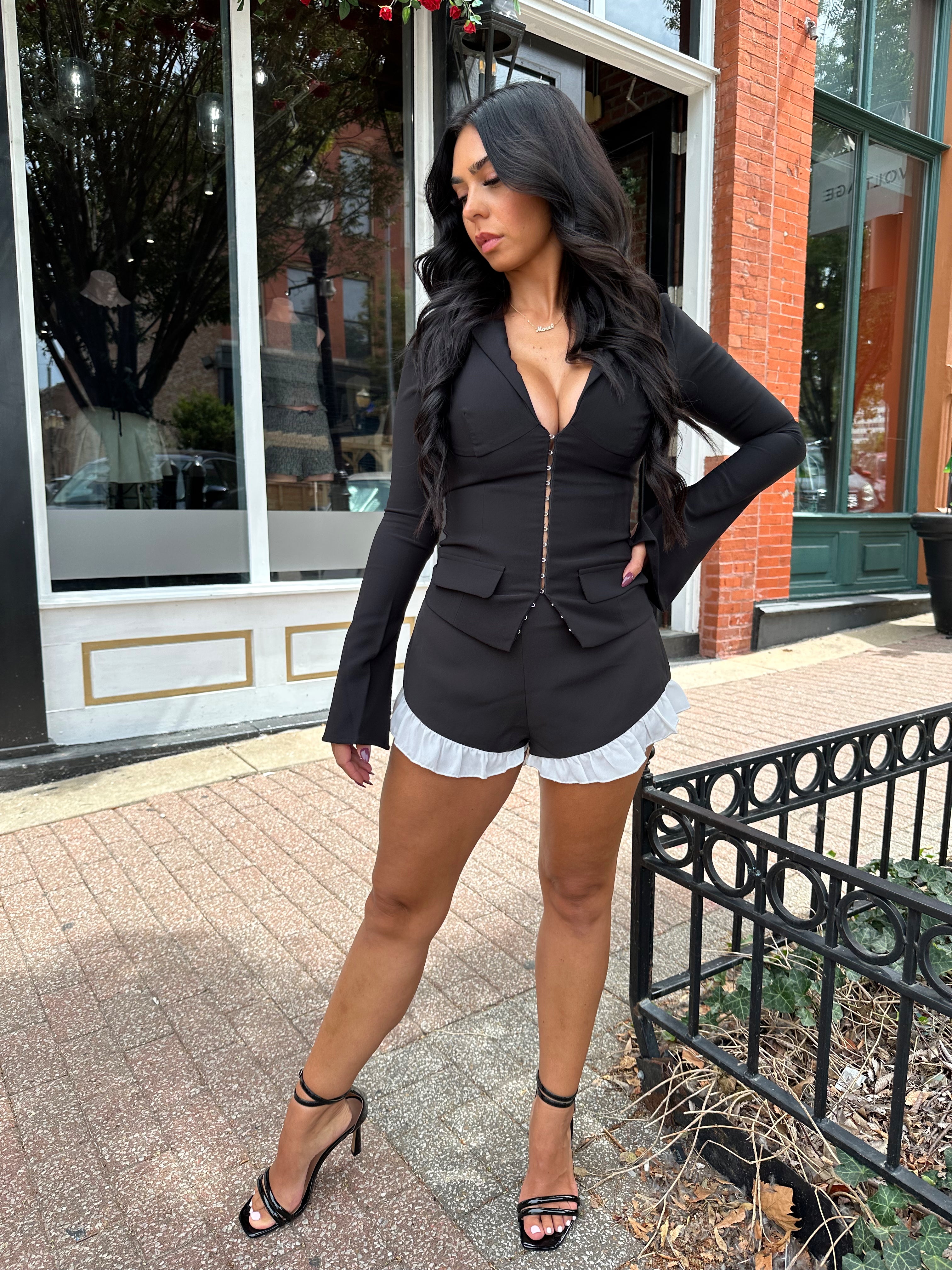 Woman wearing black long sleeve top with clasp closure. 