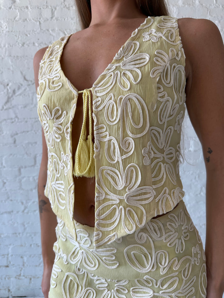Woman wearing green floral embroidered two piece set with front tie closure.
