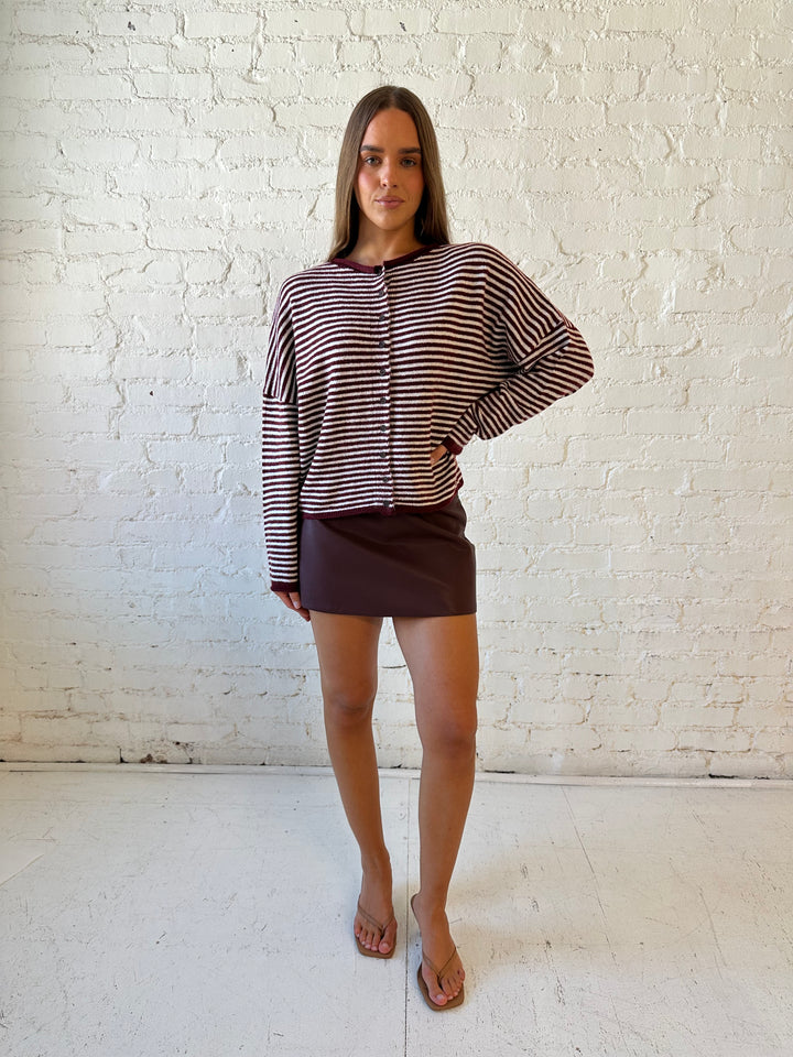 Woman wearing burgundy knit striped cardigan with burgundy leather mini skort.