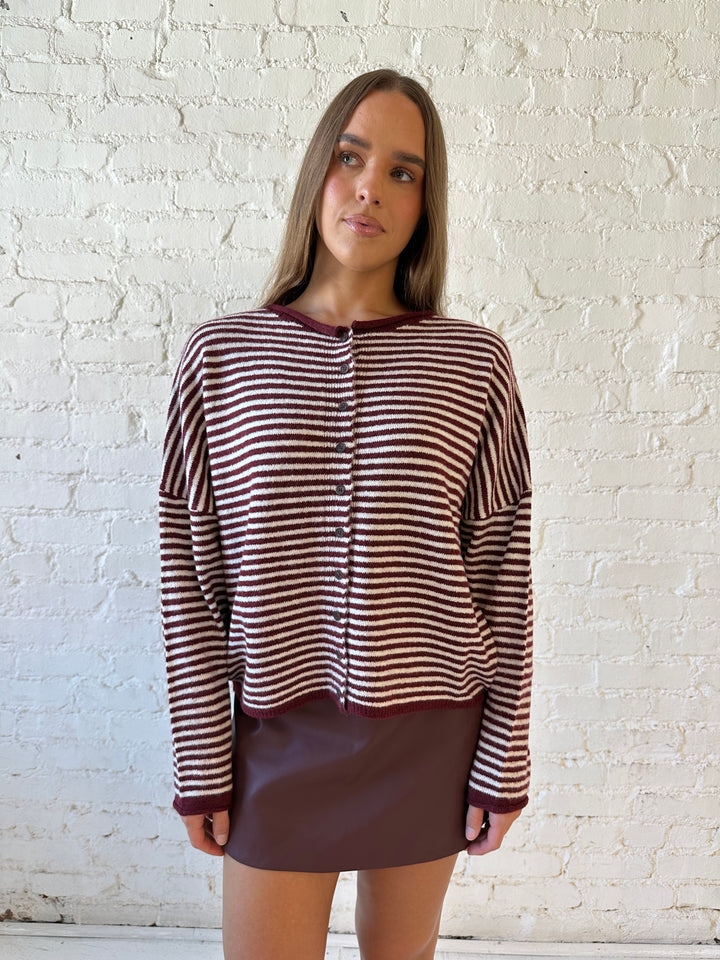 Woman wearing burgundy knit striped cardigan with burgundy leather mini skort.