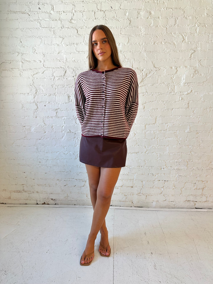 Woman wearing burgundy knit striped cardigan with burgundy leather mini skort.