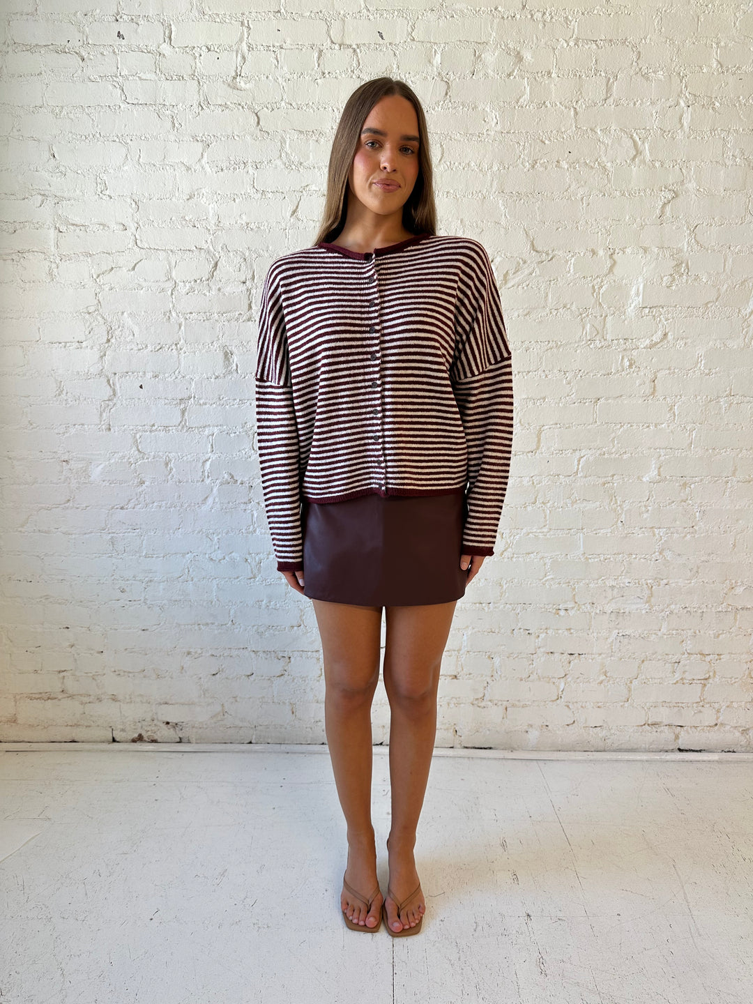 Woman wearing burgundy knit striped cardigan with burgundy leather mini skort.