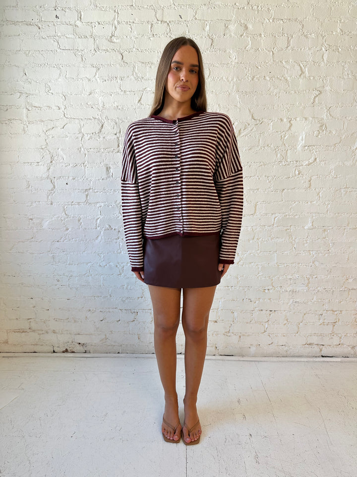 Woman wearing burgundy knit striped cardigan with burgundy leather mini skort.