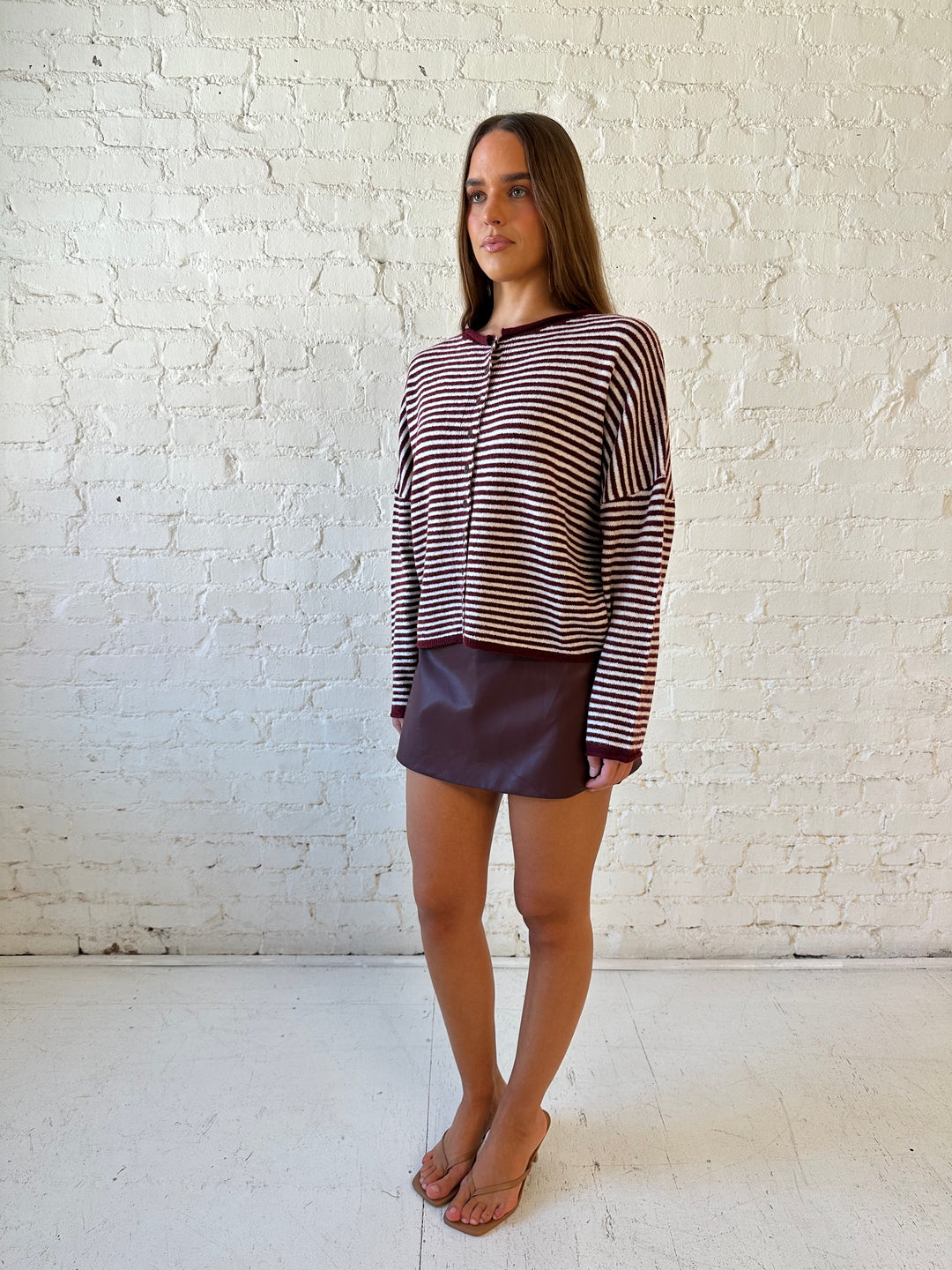 Woman wearing burgundy knit striped cardigan with burgundy leather mini skort.