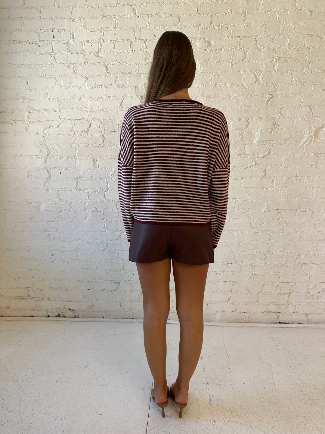 Woman wearing burgundy knit striped cardigan with burgundy leather mini skort.