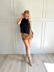 Woman wearing a black knit sleeveless sweater top with tie side detail.