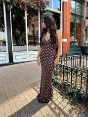 Woman wearing brown polka dot mesh maxi dress with v-neckline. 