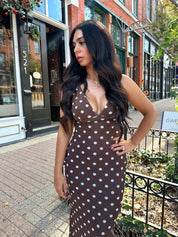 Woman wearing brown polka dot mesh maxi dress with v-neckline. 