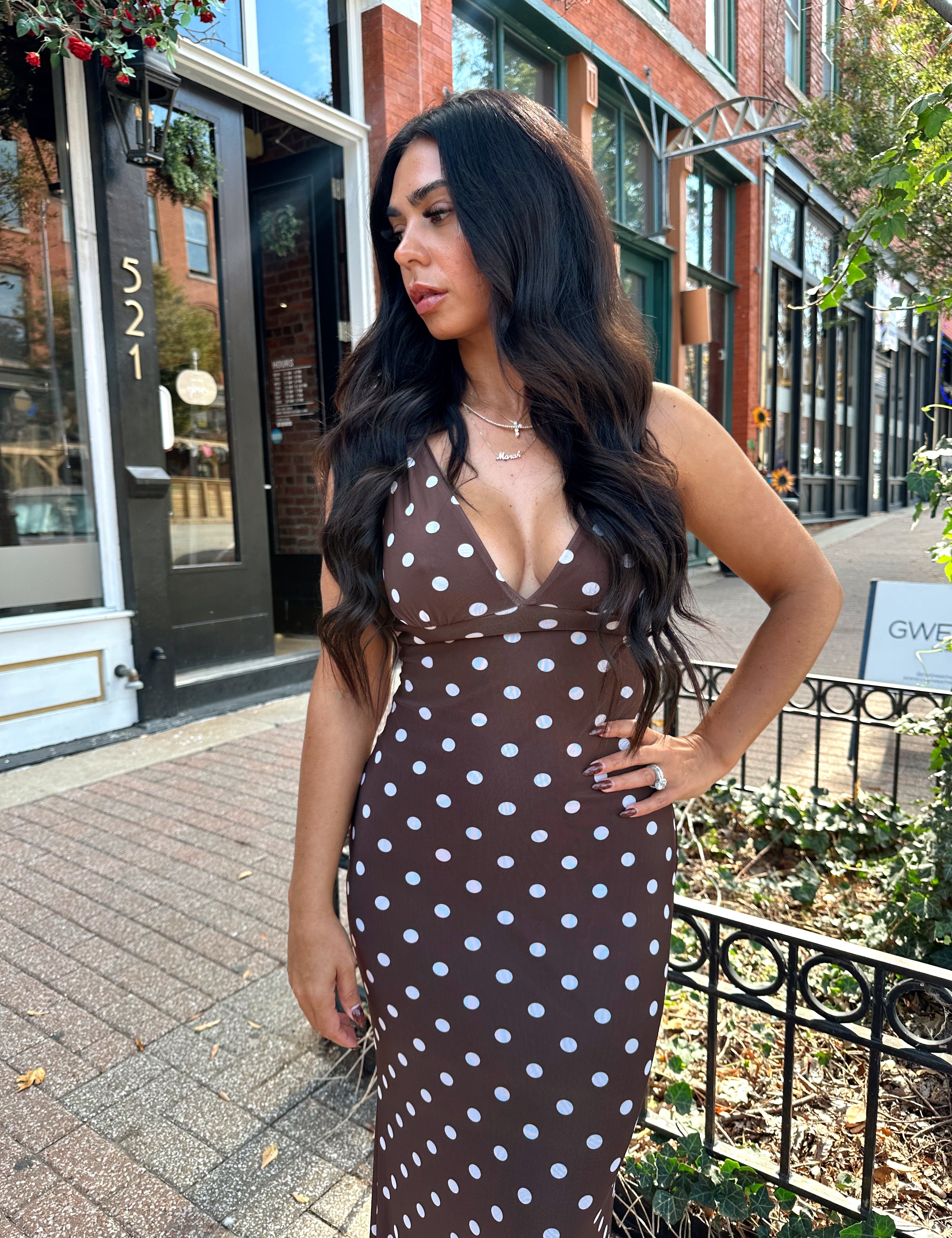 Woman wearing brown polka dot mesh maxi dress with v-neckline. 