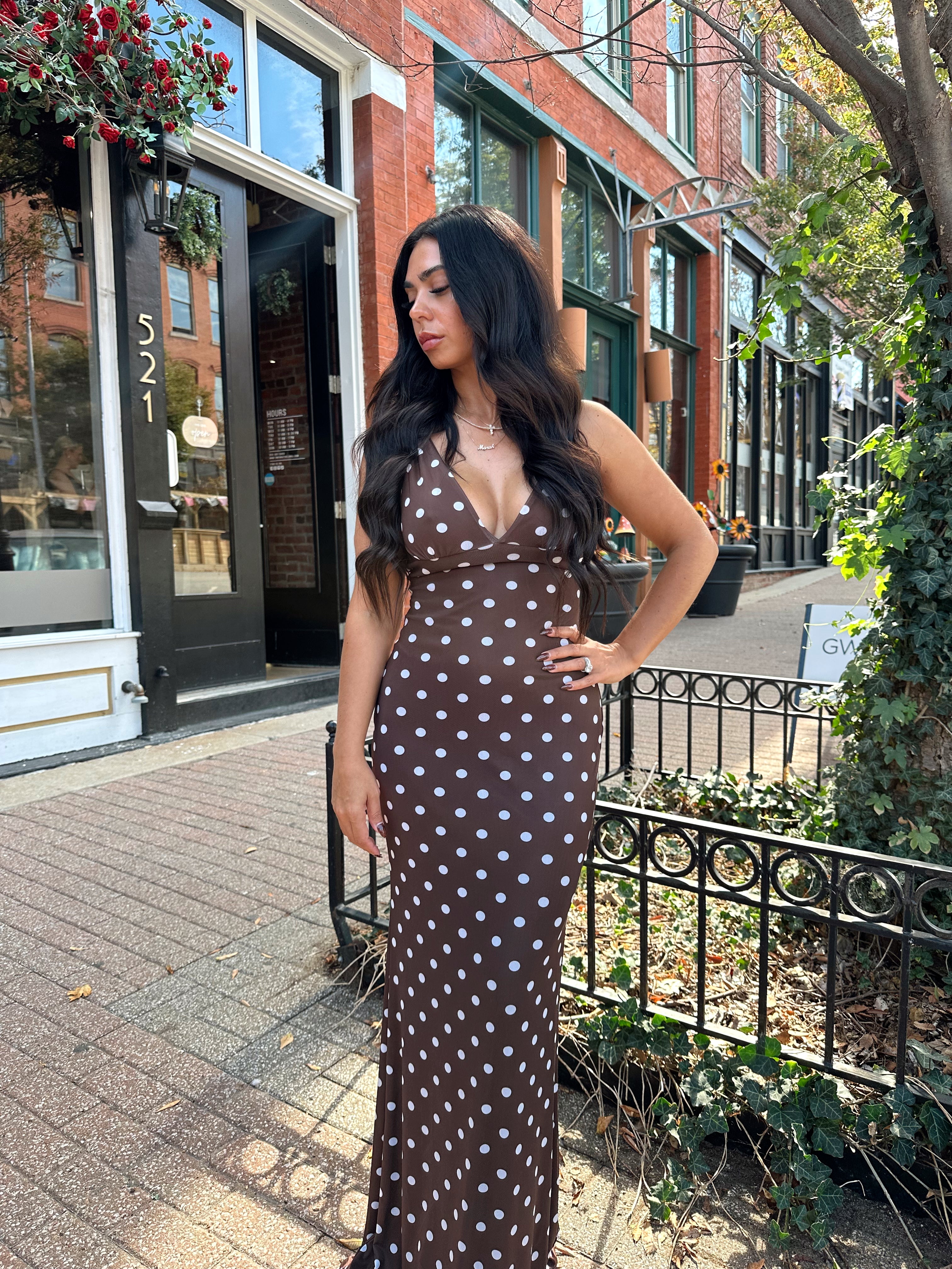 Woman wearing brown polka dot mesh maxi dress with v-neckline. 