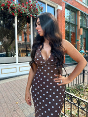 Woman wearing brown polka dot mesh maxi dress with v-neckline. 