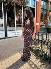 Woman wearing brown polka dot mesh maxi dress with v-neckline. 