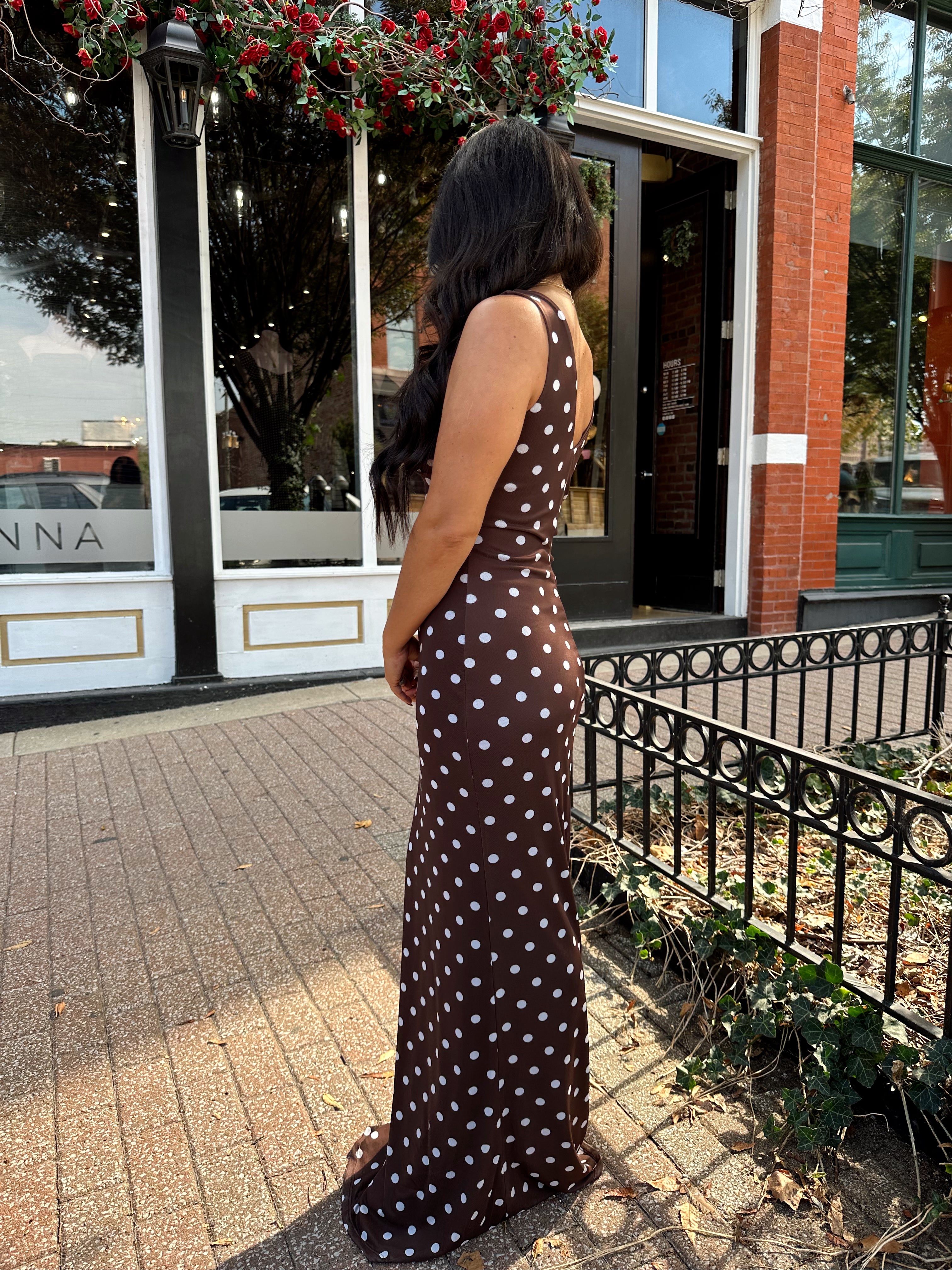 Woman wearing brown polka dot mesh maxi dress with v-neckline. 
