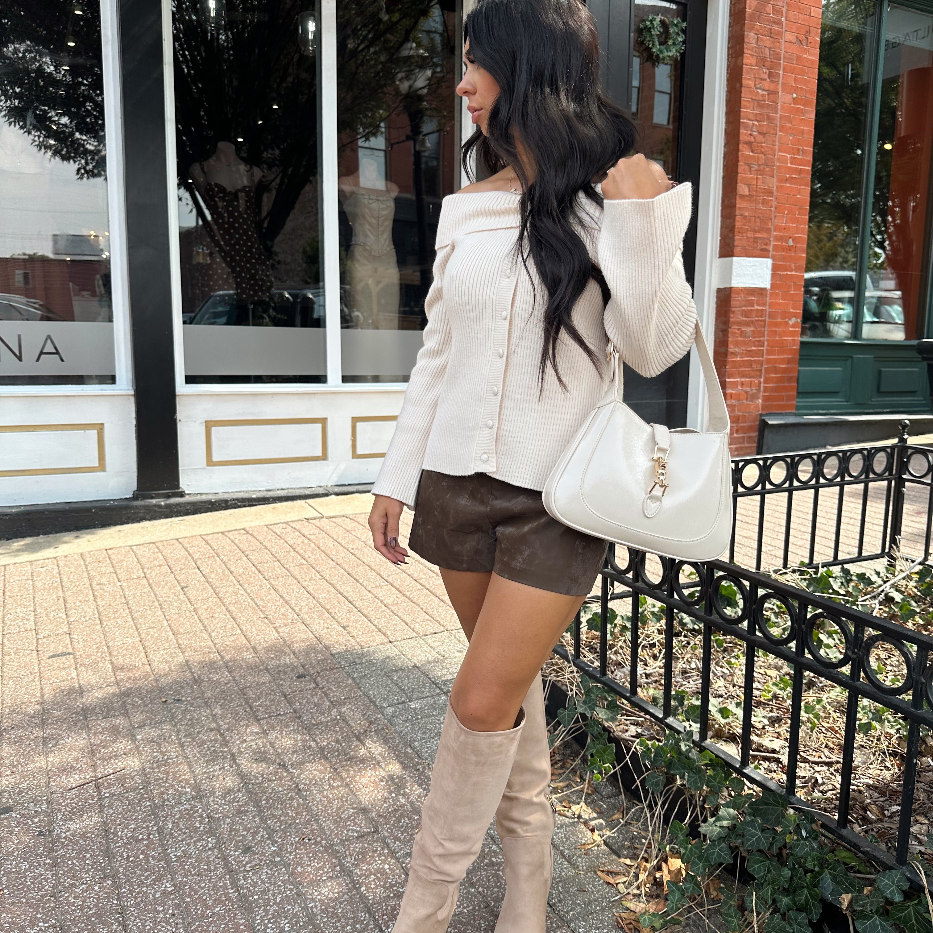 Woman wearing cream off the shoulder long sleeve ribbed top with button detail.