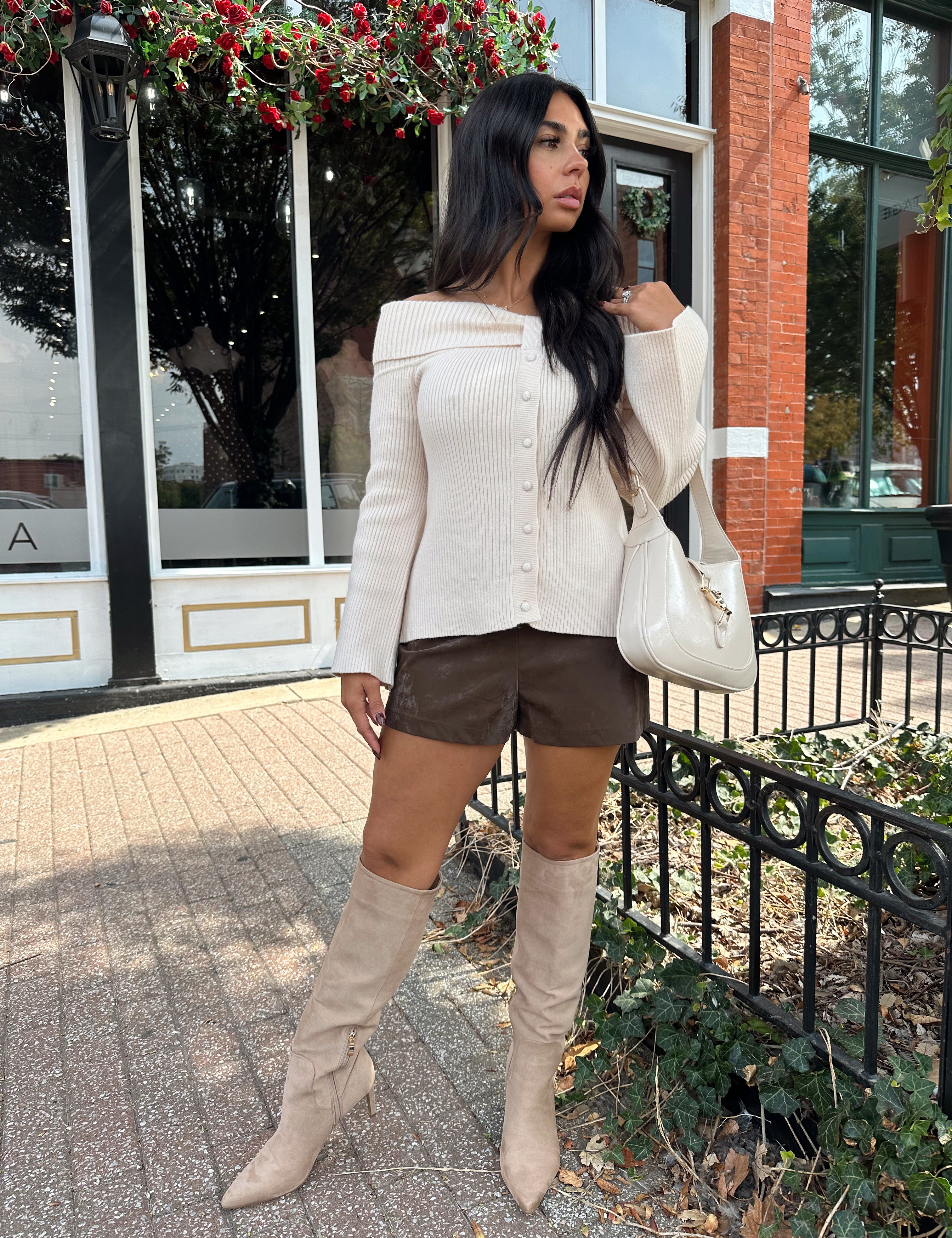 Woman wearing cream off the shoulder long sleeve ribbed top with button detail.