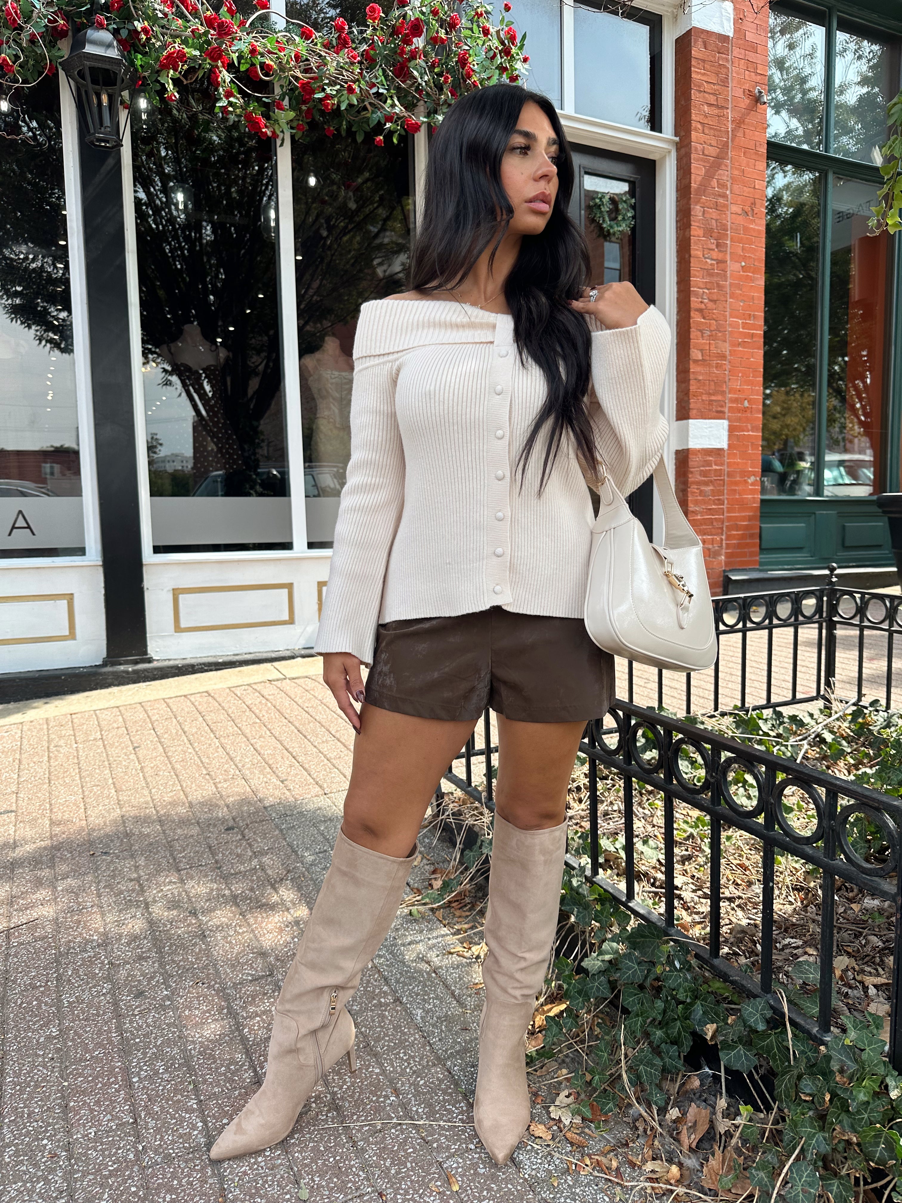 Woman wearing cream off the shoulder long sleeve ribbed top with button detail.