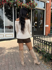Woman wearing cream off the shoulder long sleeve ribbed top with button detail.