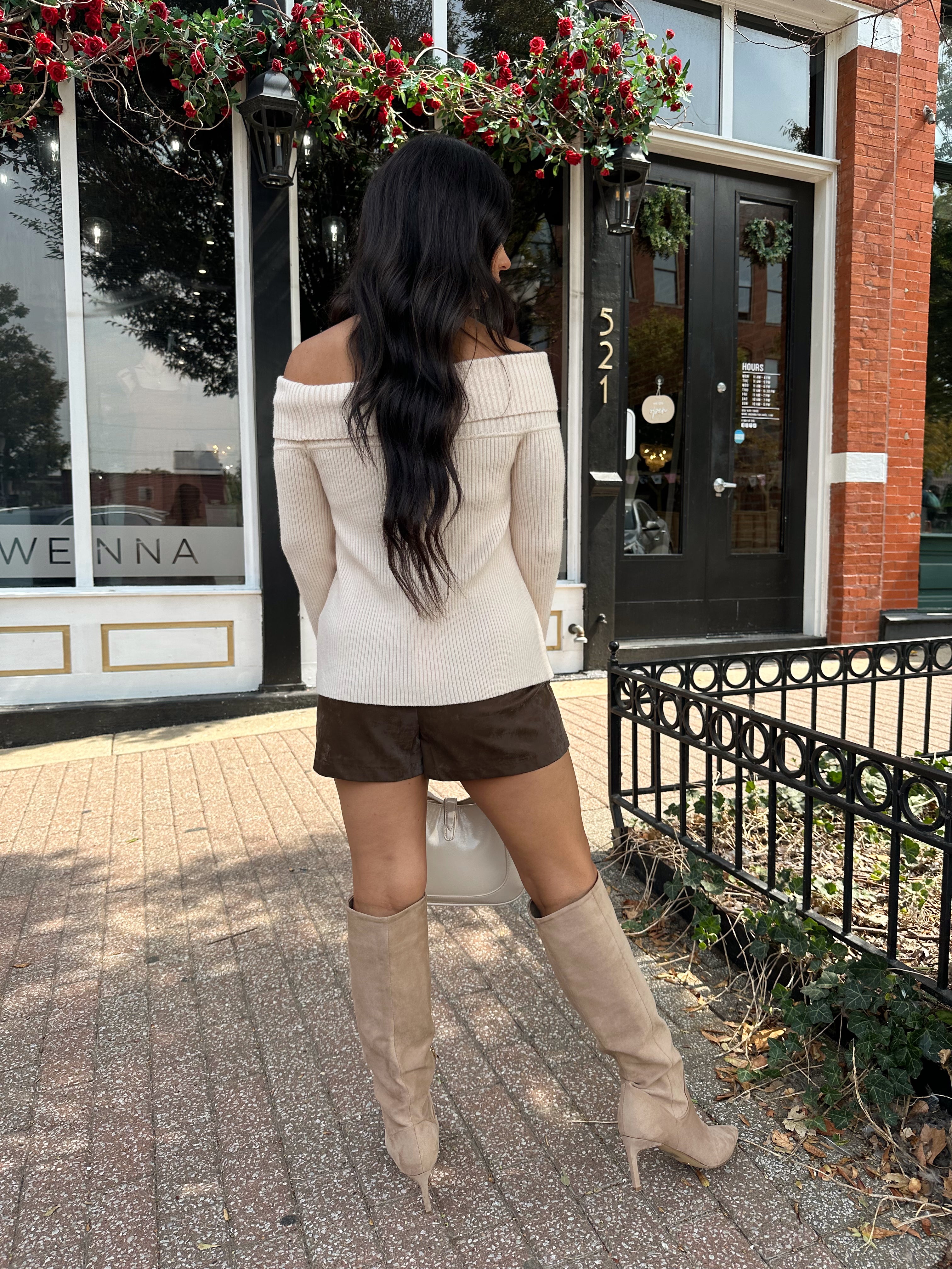 Woman wearing cream off the shoulder long sleeve ribbed top with button detail.