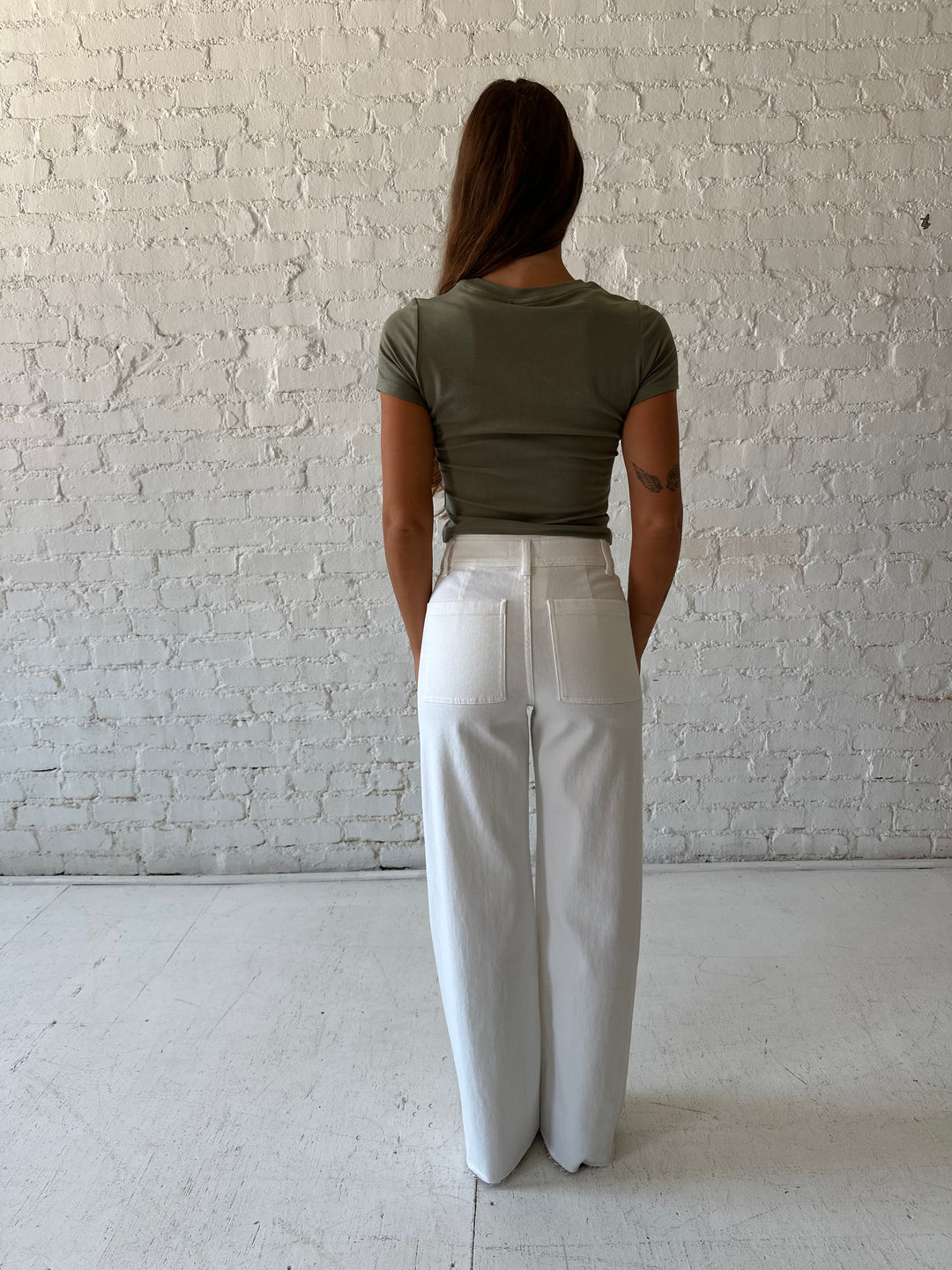 Woman wearing white high waisted wide leg jean with olive green top.