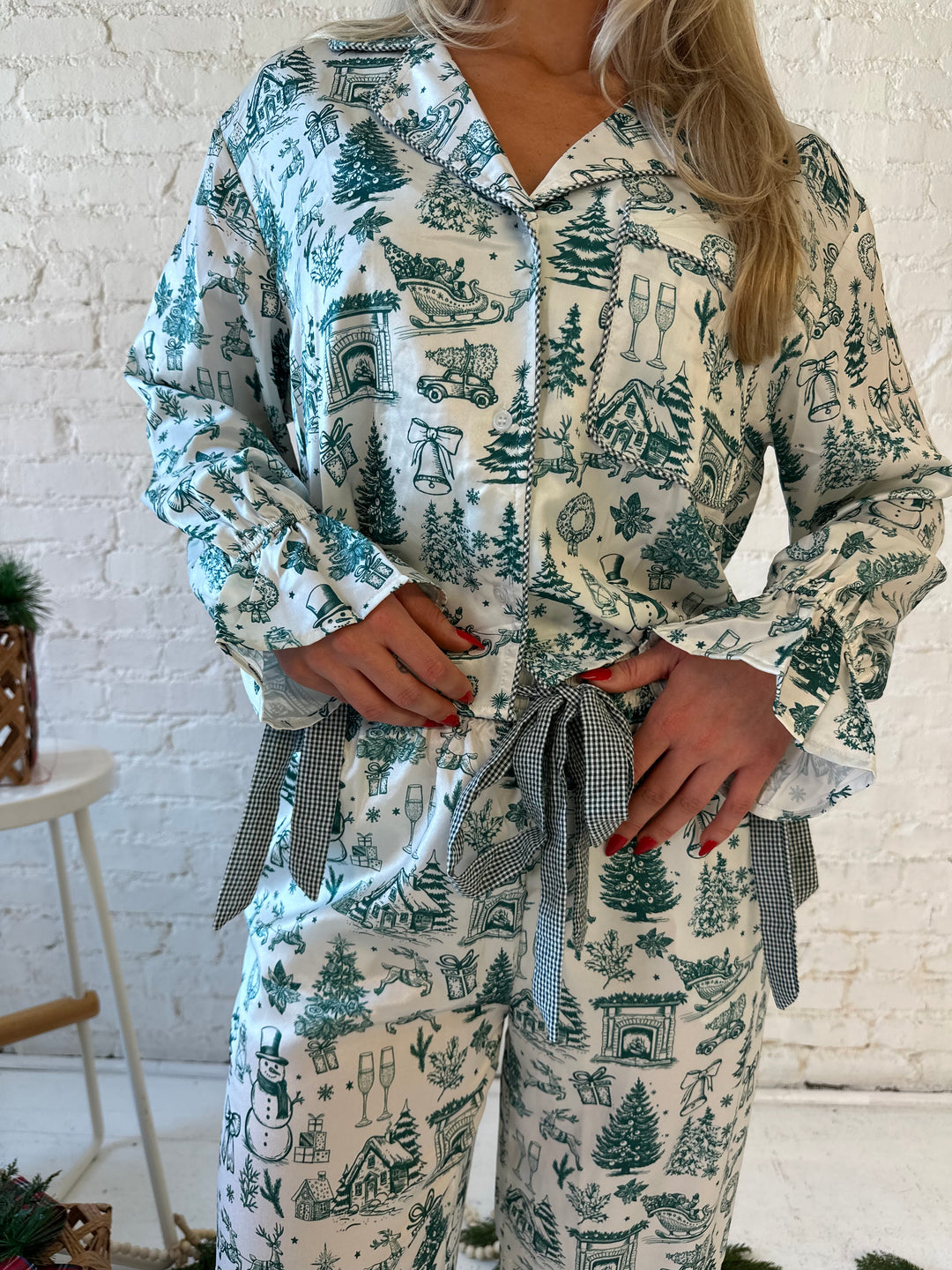 Woman wearing green and white pattern satin pajama set with long sleeve button down top, and long pants.