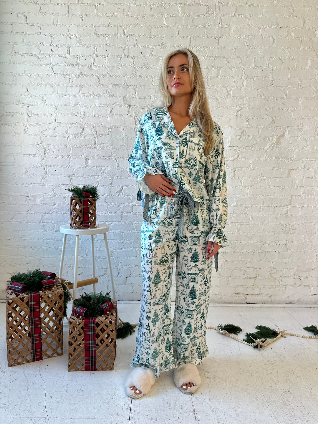 Woman wearing green and white pattern satin pajama set with long sleeve button down top, and long pants.