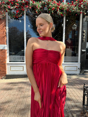 Woman wearing strapless red plissé maxi dress with lace up back, and detachable scarf.