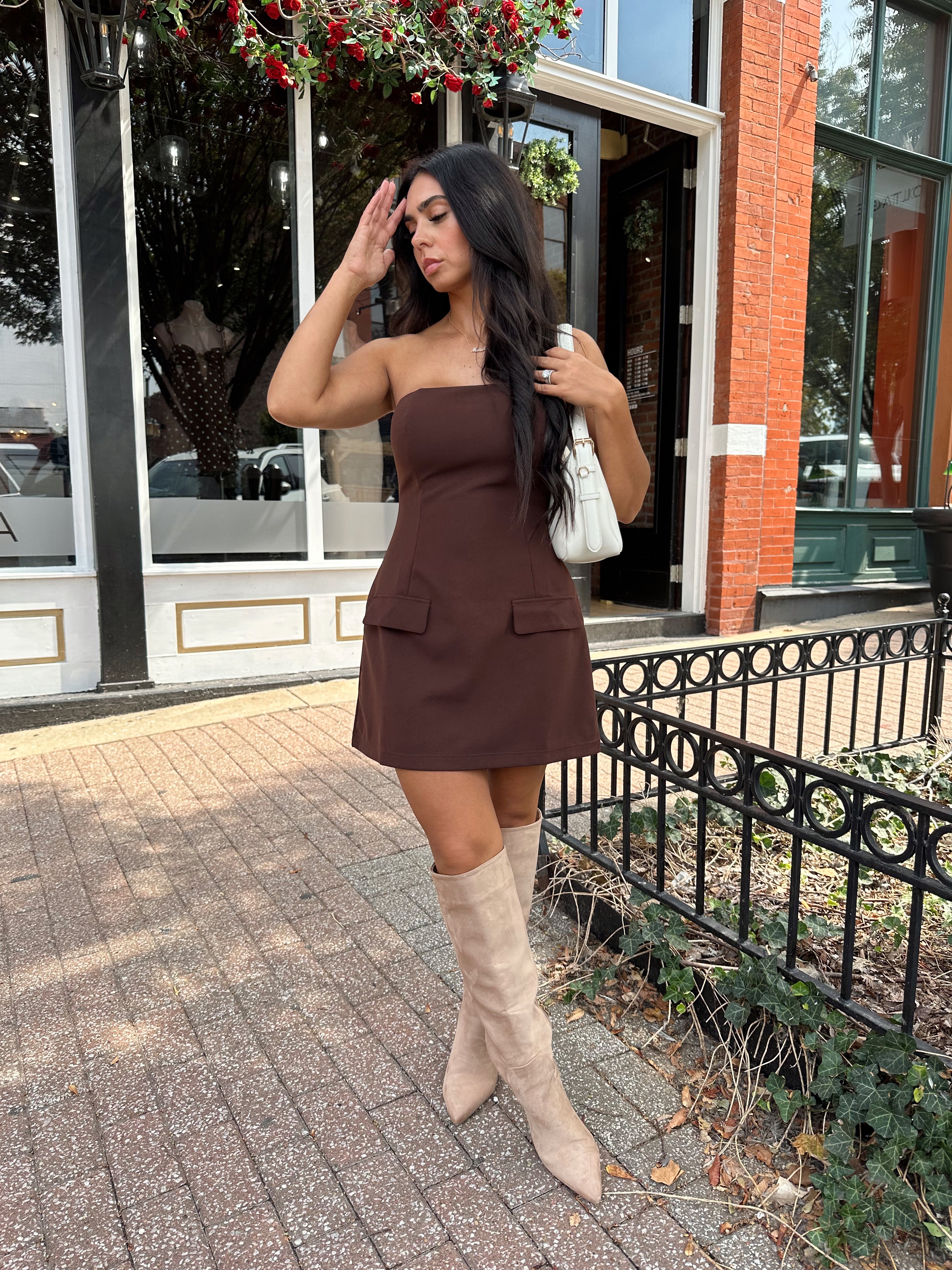 Woman wearing dark brown tailored mini dress with front pockets and built in shorts. 