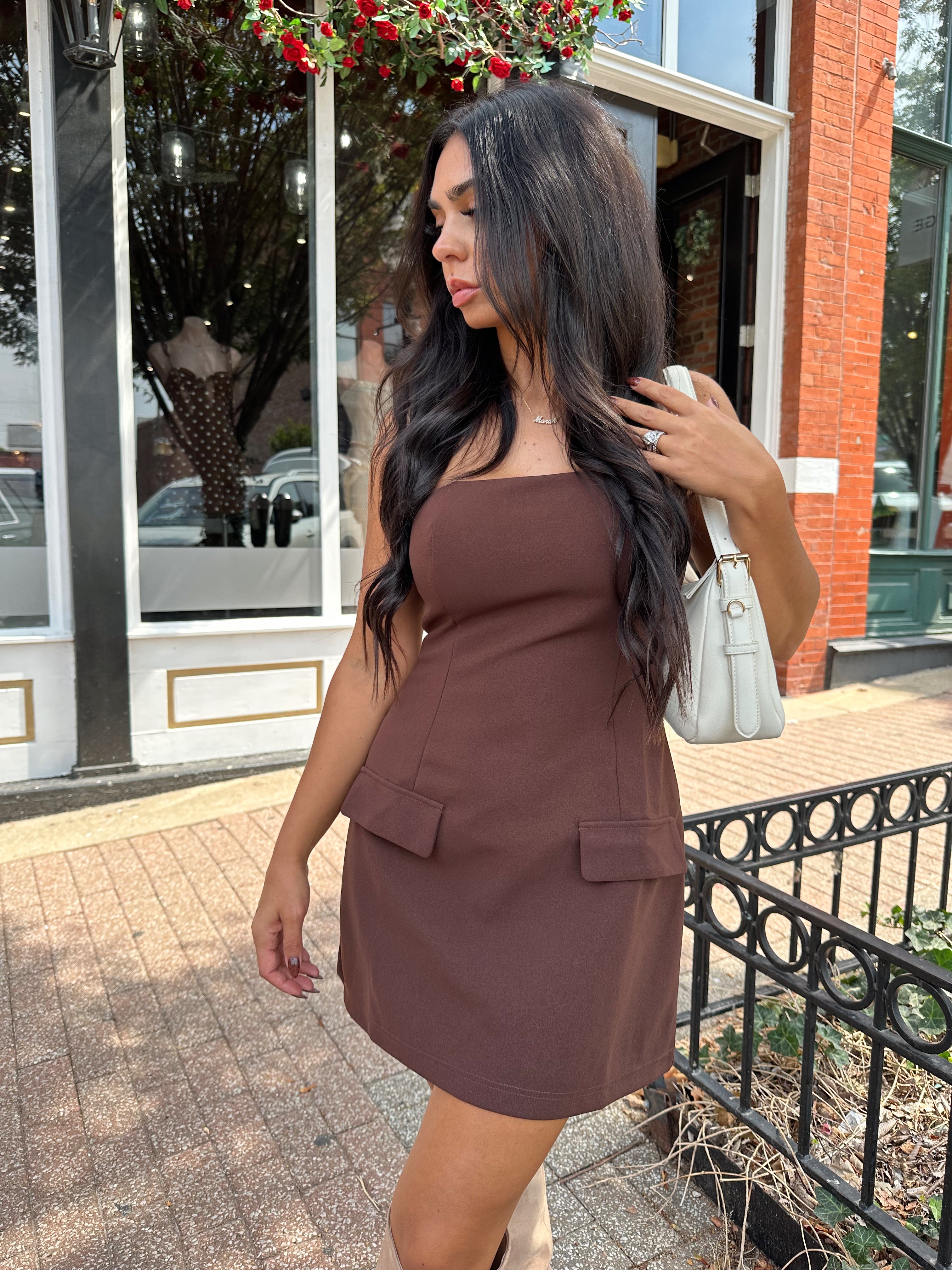 Woman wearing dark brown tailored mini dress with front pockets and built in shorts. 