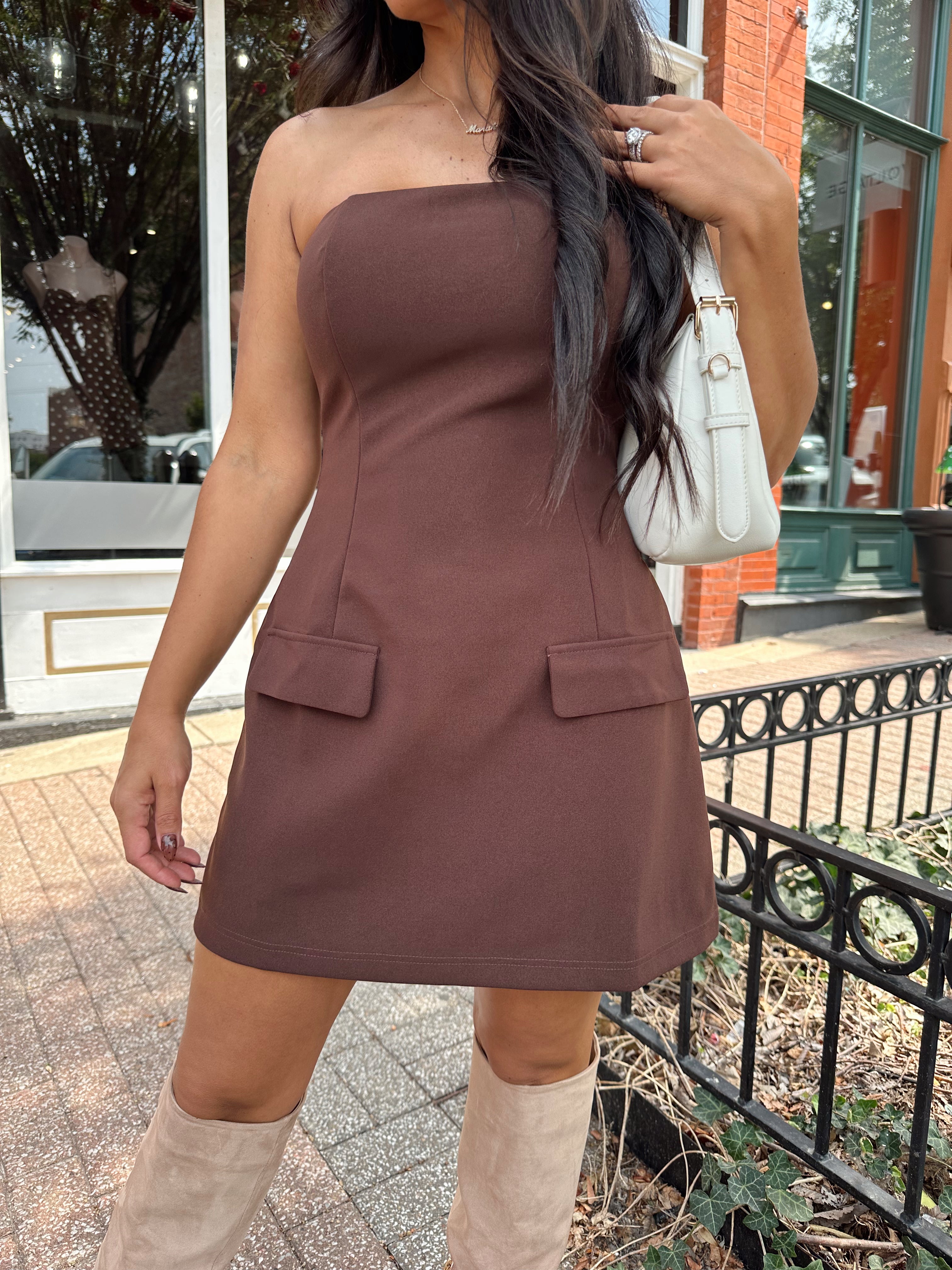Woman wearing dark brown tailored mini dress with front pockets and built in shorts. 